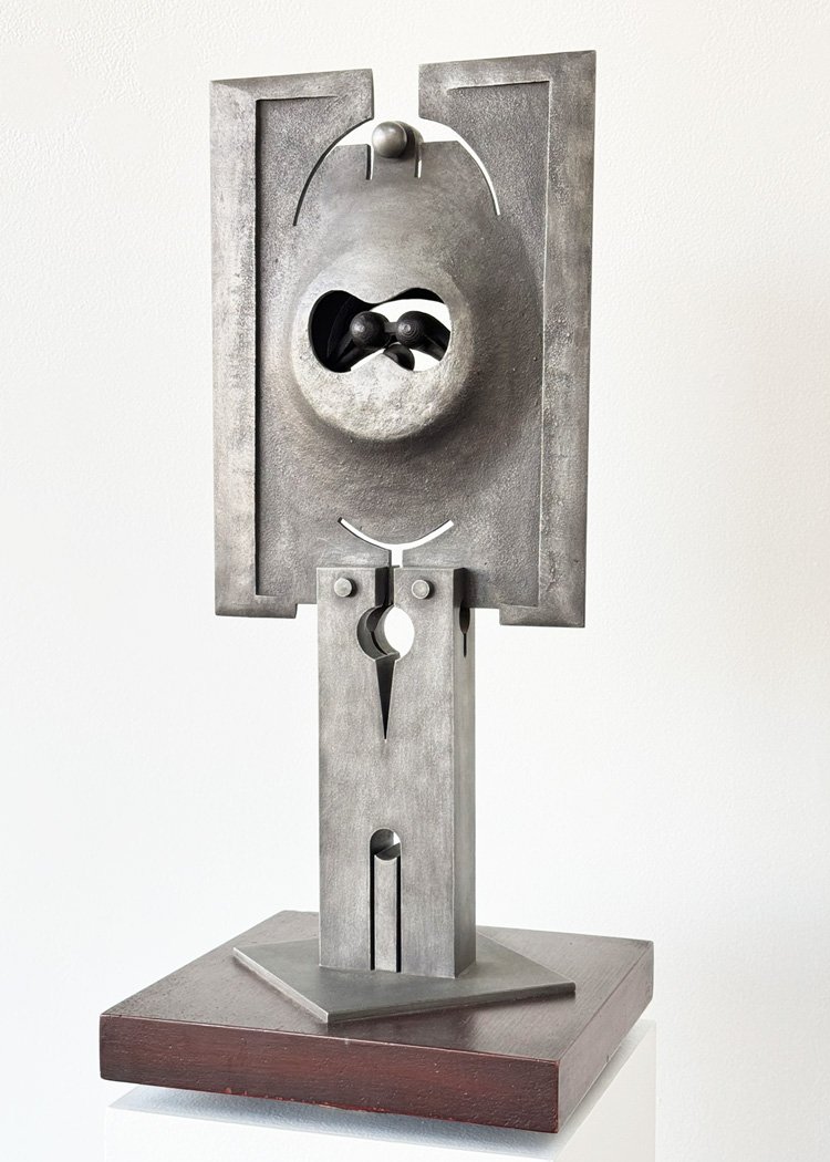 Abstract metal sculpture by Angelo Granata with geometric shapes and circular cutouts, mounted on a wooden base.