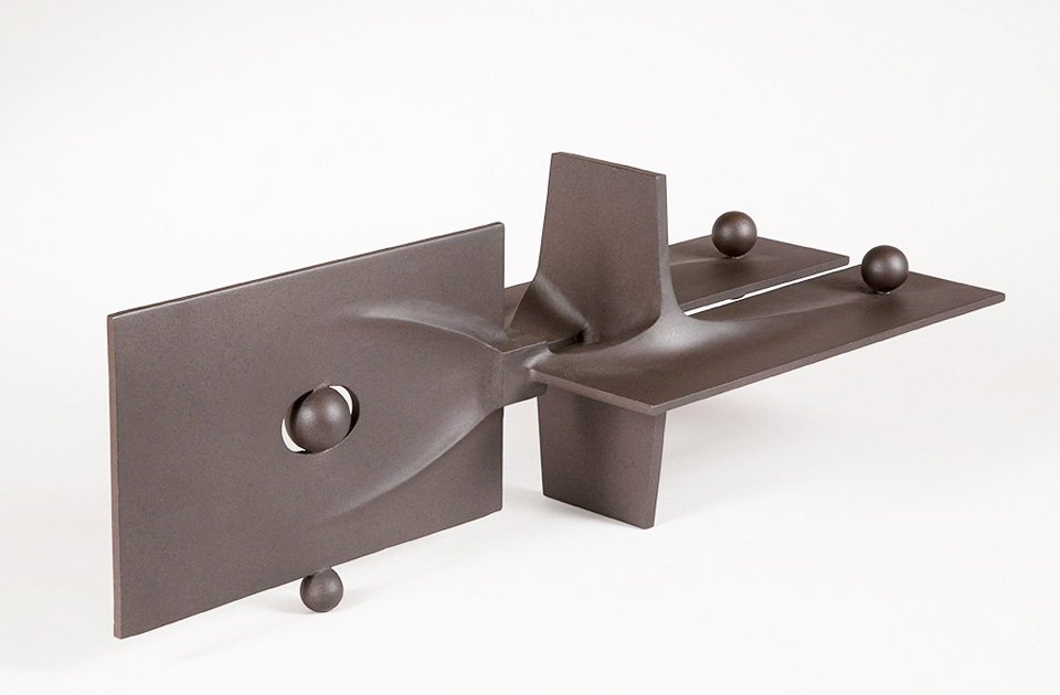 Abstract metal sculpture by Angelo Granata with geometric shapes and spherical elements on a white background.
