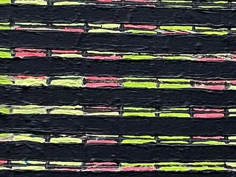 Close-up of a colorful abstract painting with black, pink, green, and yellow threads.
