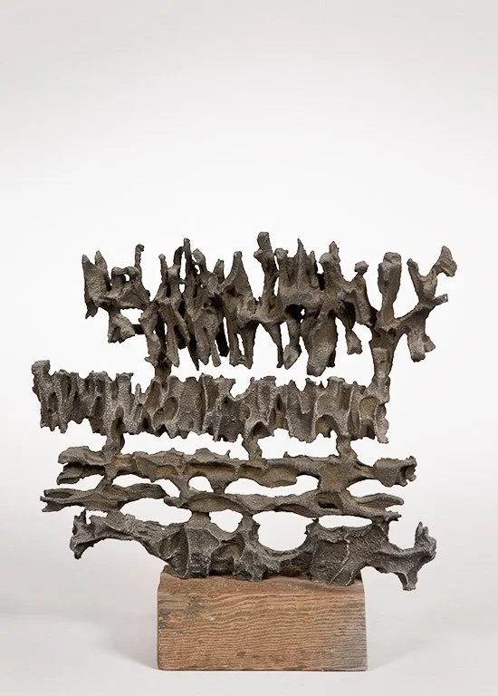 Abstract metal sculpture by Angelo Granata with irregular, porous shapes on a wooden base, resembling natural formations or coral-like structures.