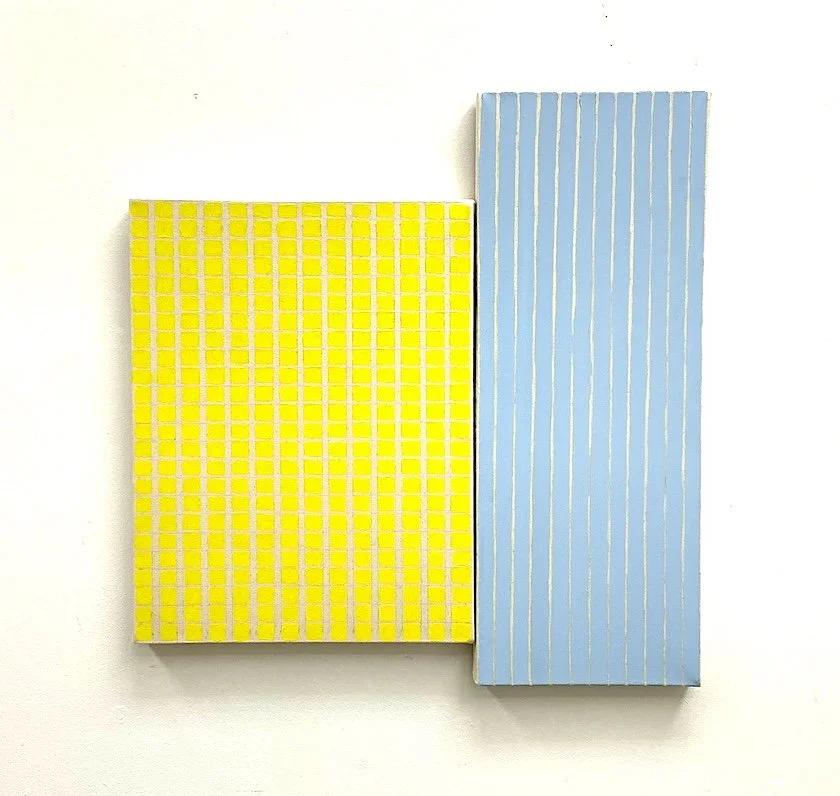 Two rectangular paintings, a yellow grid-like item on the left and a light blue striped item on the right, mounted on a white wall.