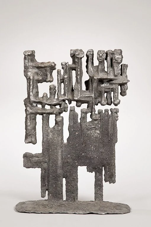 Abstract metal sculpture titled HETEROS by Angelo Granata with intricate geometric forms and a textured surface against a plain background.
