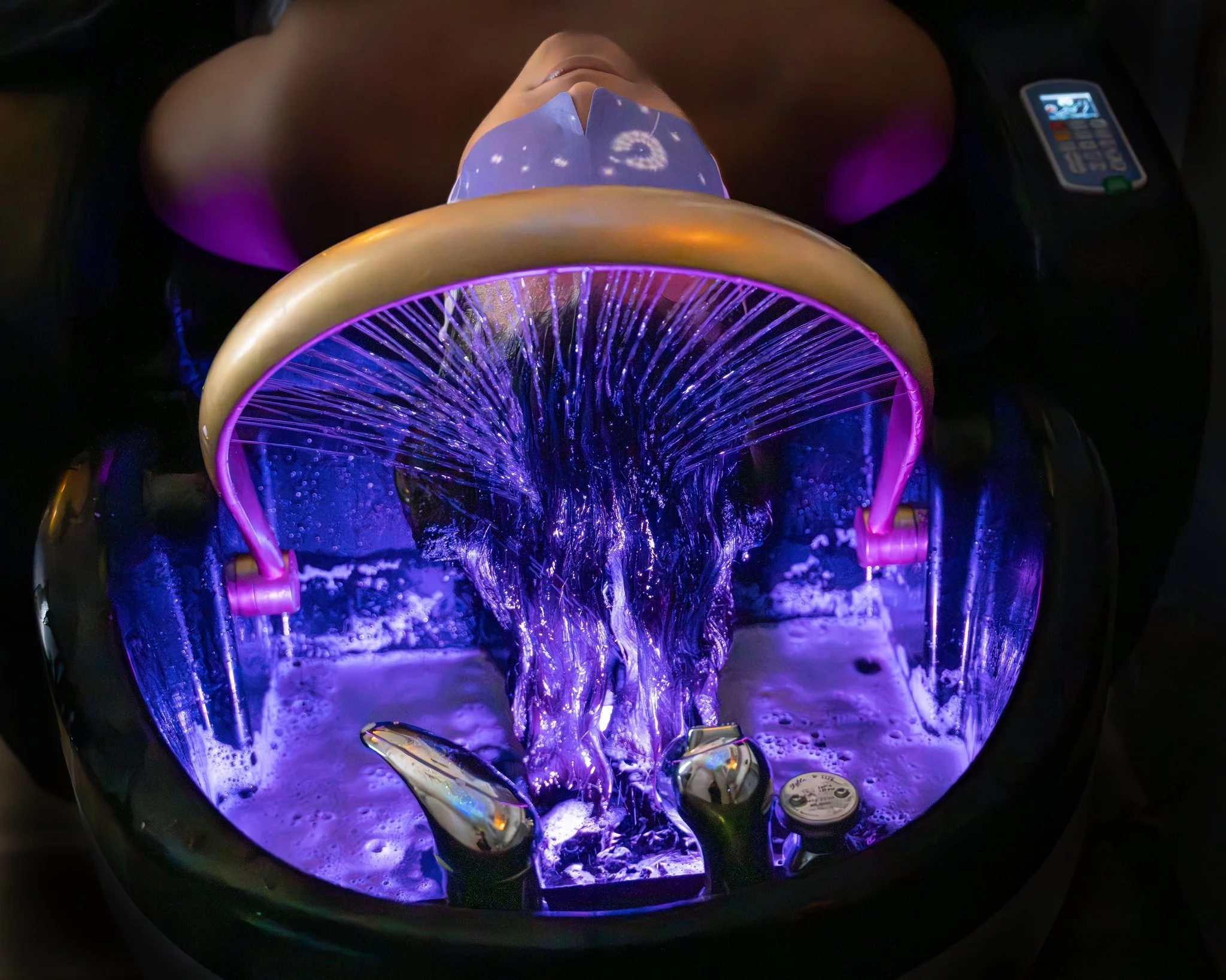 Woman laying in head spa bed receiving a relaxing treatment and hair washing