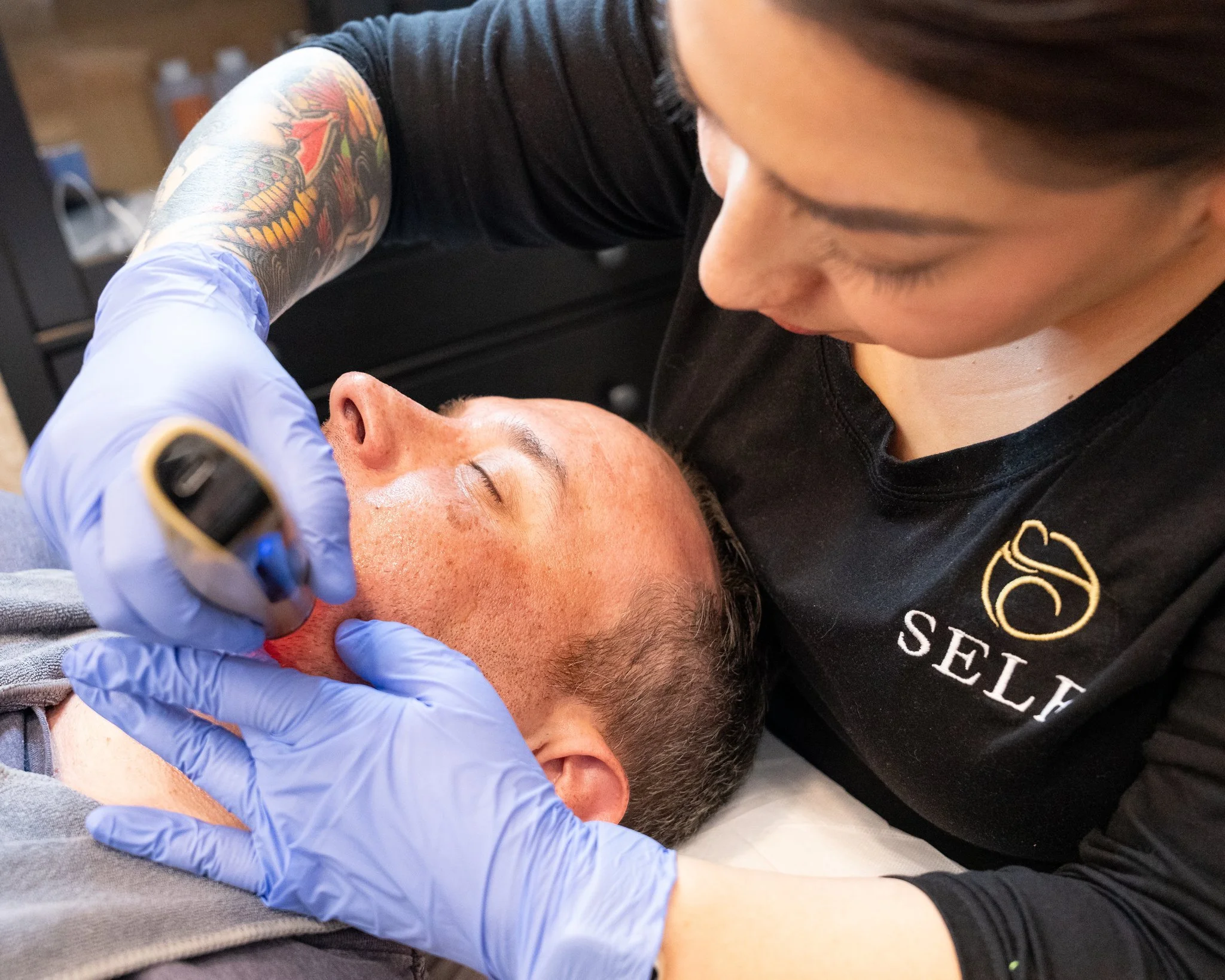 A smiling young man with blond hair, showing white teeth, and looking slightly to the side.