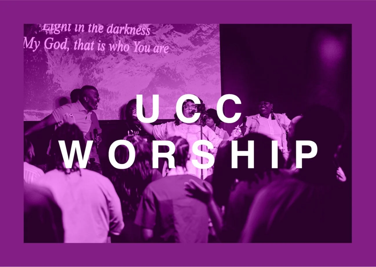A group of people singing and worshipping on a stage with a purple overlay. The words 'UCC WORSHIP' are overlaid in large white text. A background projection displays the words 'Light in the darkness My God, that is who You are' in pink.