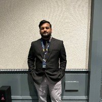 Man in a suit standing against a beige and gray wall