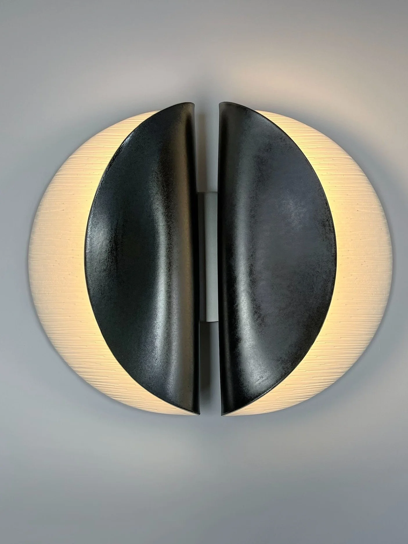 A modern wall-mounted light fixture with a circular design, by Olivia Barry of Olivia Barry by Hand, New York-based lighting designer