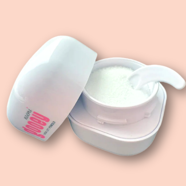 Valkoinen purkki sisältää valkoista voiteen tai balmin kaltaista ainetta, ja siihen on laitettu pieni kaavin, kaikki aseteltu vaaleanpunaiselle taustalle.