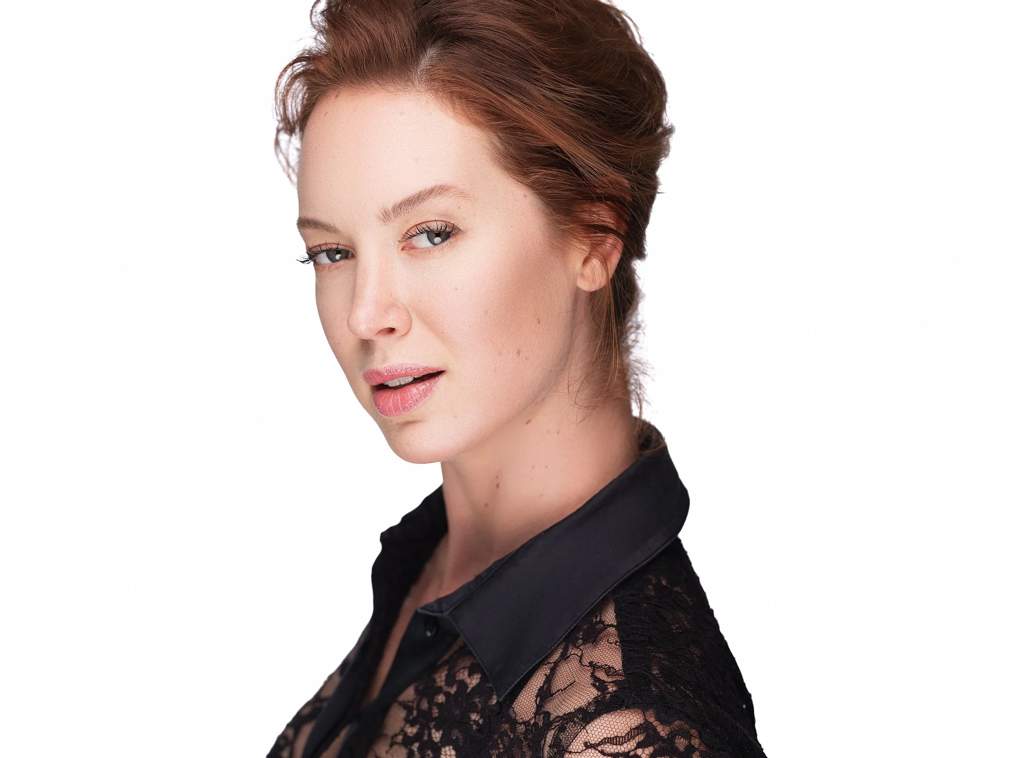 Woman in black lace clothing with light skin and styled hair, against a plain white background.