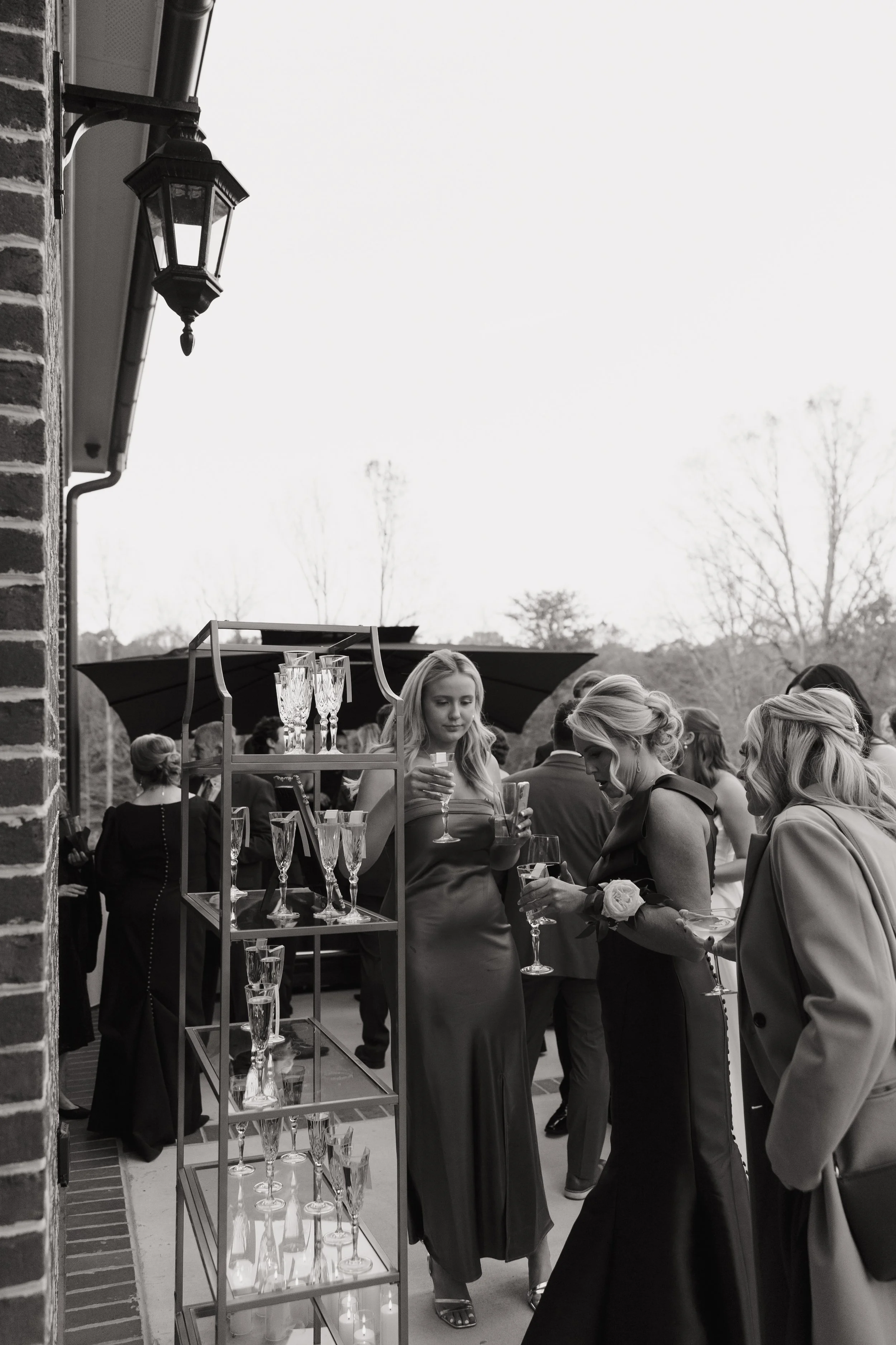 Women in evening dresses holding glasses of wine at an outdoor party