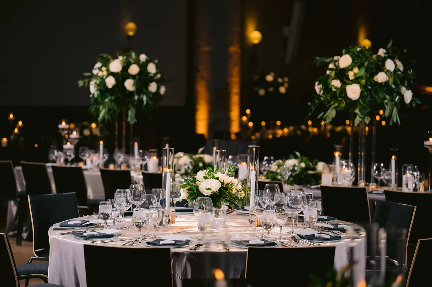 Modern supper club wedding reception layout with long tables and moody candle lighting.