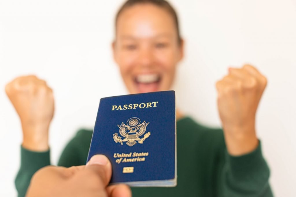 Persona feliz mostrando un pasaporte de los Estados Unidos de América con los puños en señal de victoria.
