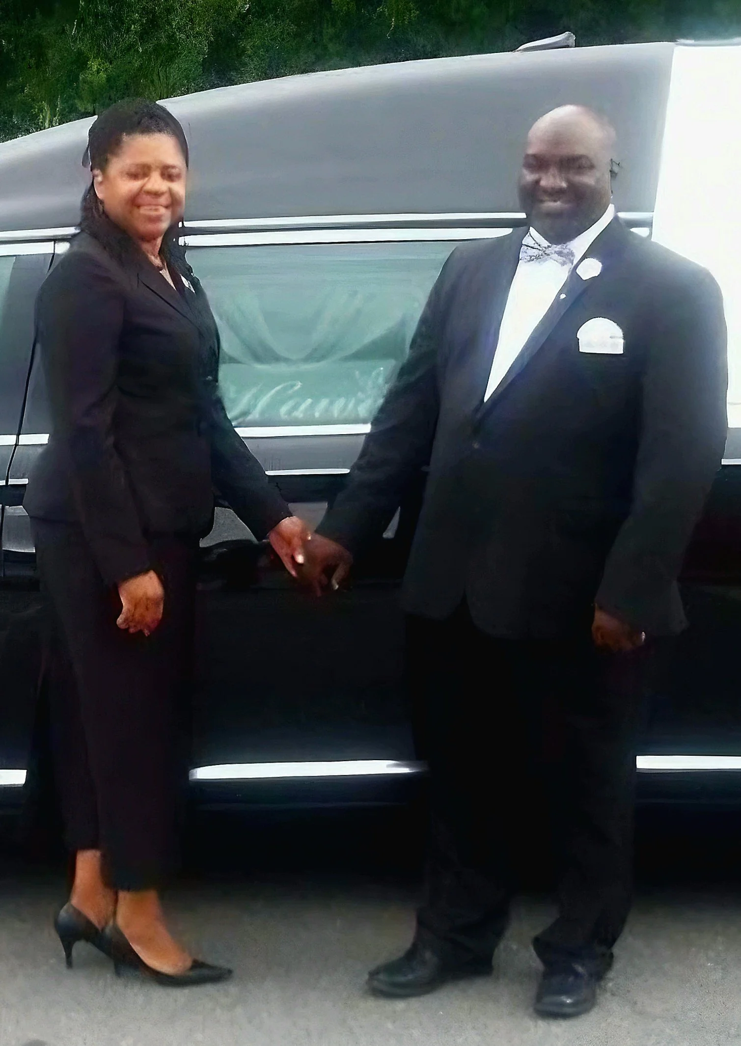 A woman and a man in formal attire shaking hands in front of a hearse.