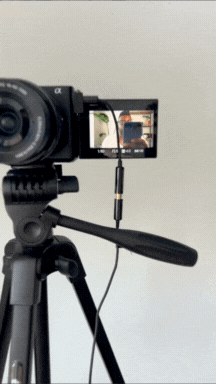 Camera mounted on tripod recording a scene with a monitor view of the scene.