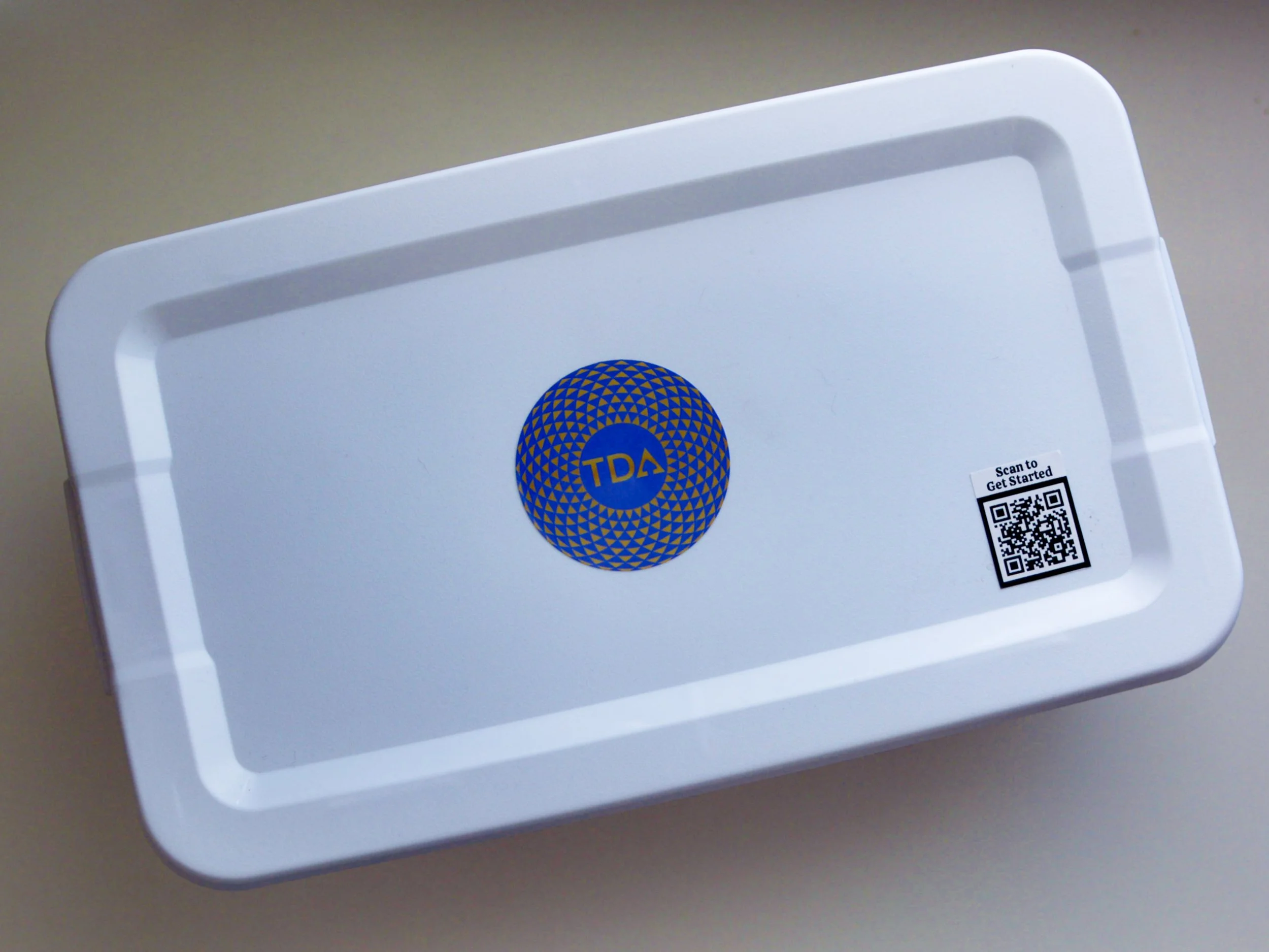 A white plastic container with a blue circular logo in the center and a QR code sticker on the side that says "Scan to Get Started".