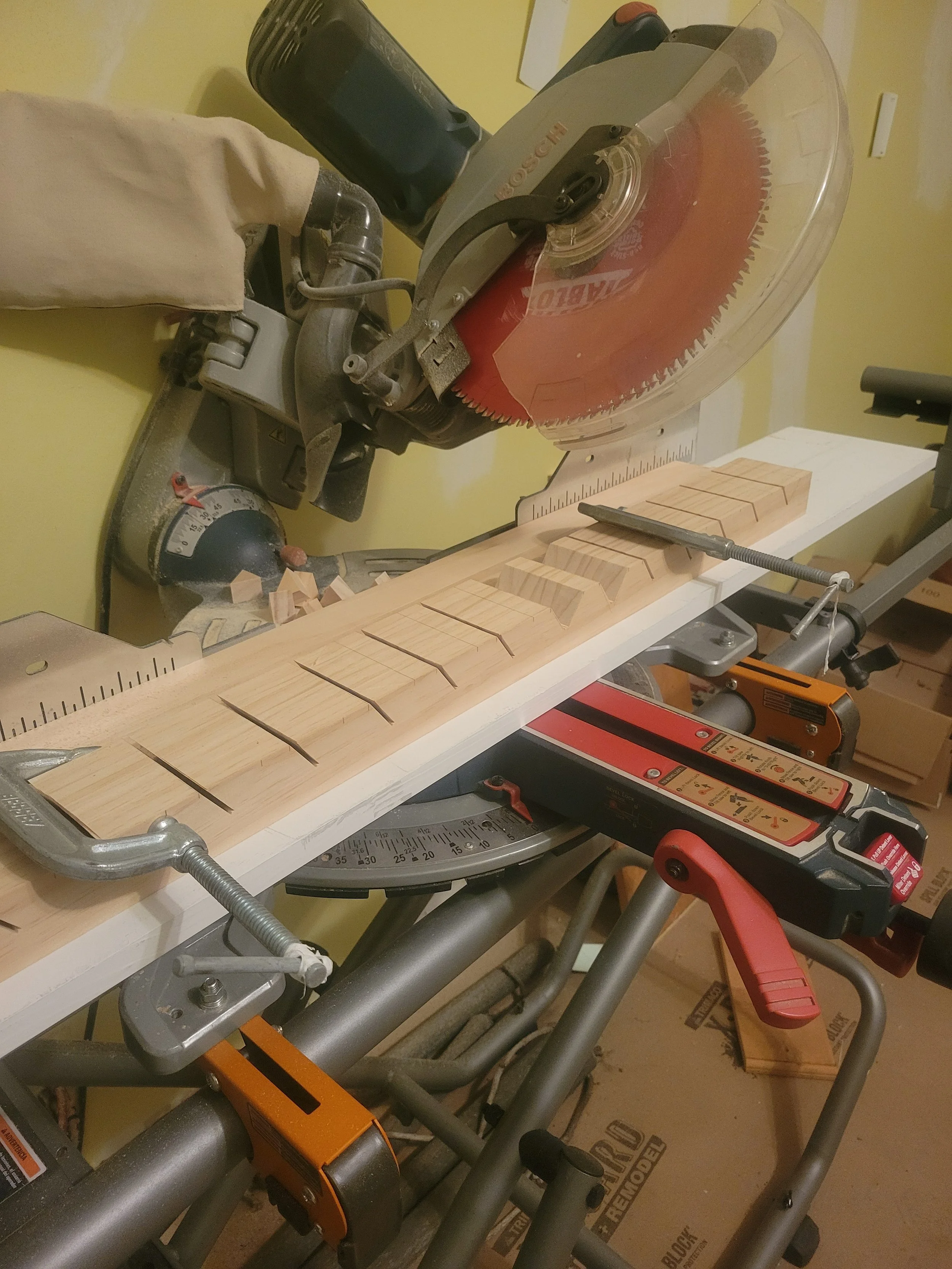 A miter saw on a workbench with wooden pieces cut and clamped, set up for a woodworking project.