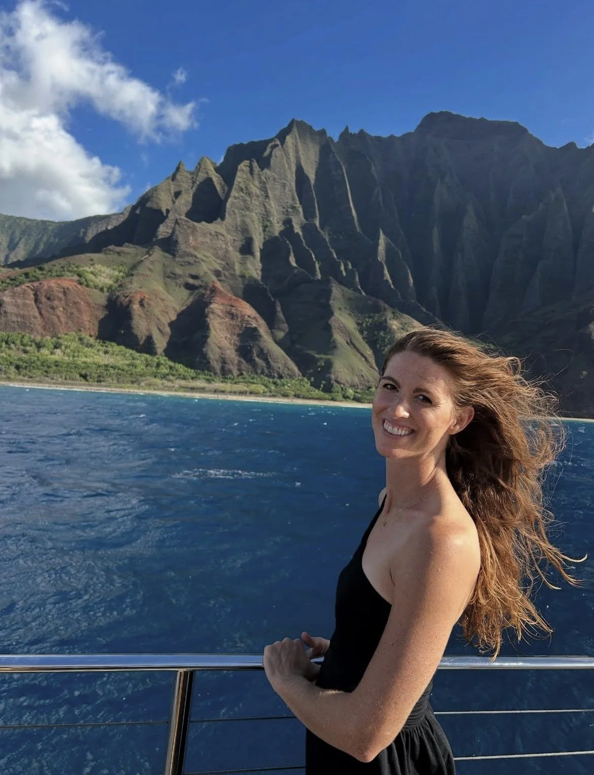 Julianne Penner, PA-C, RD, smiling on a boat along Kauai's Nā Pali Coast