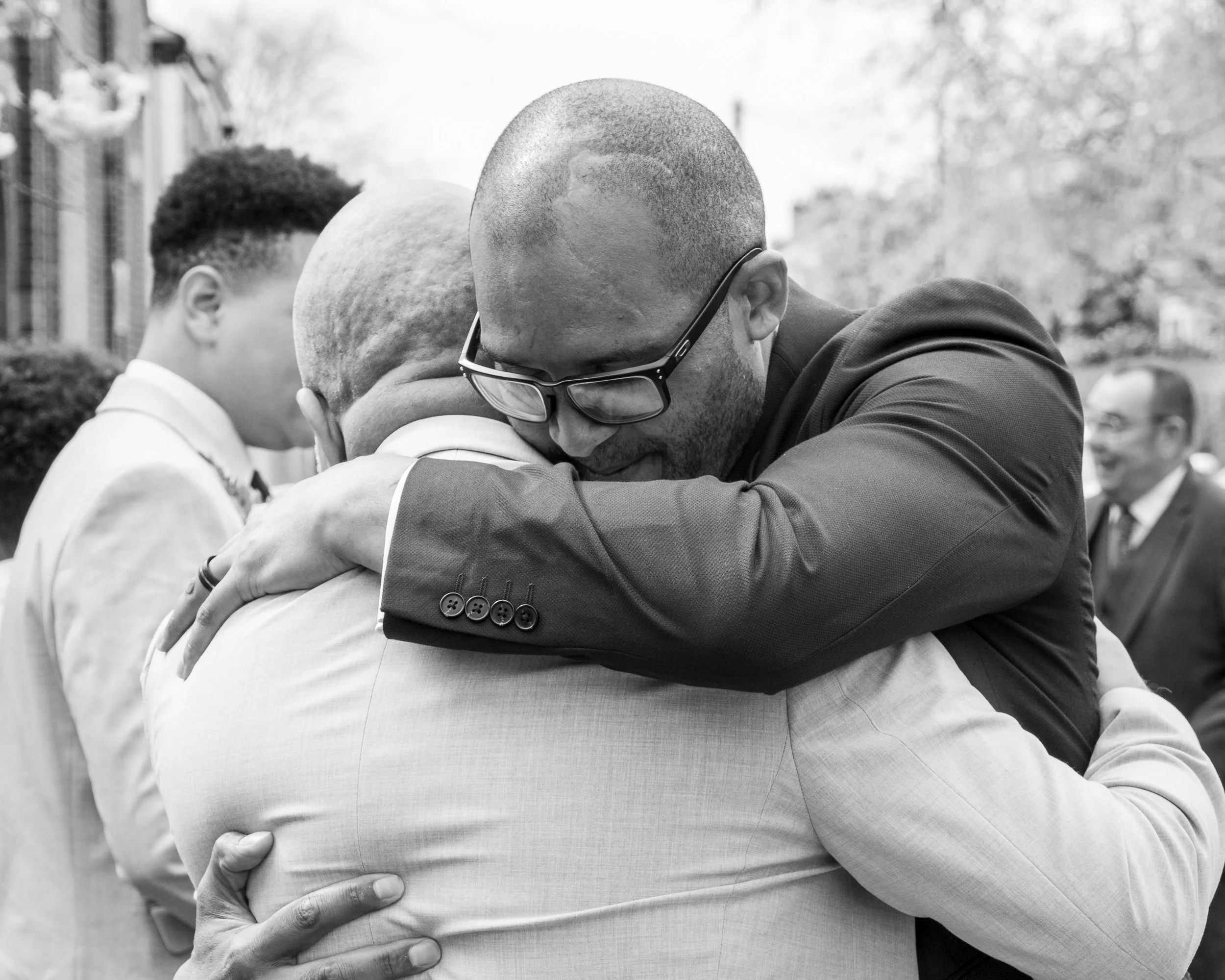 People embracing in a tight hug outdoors, in black and white.