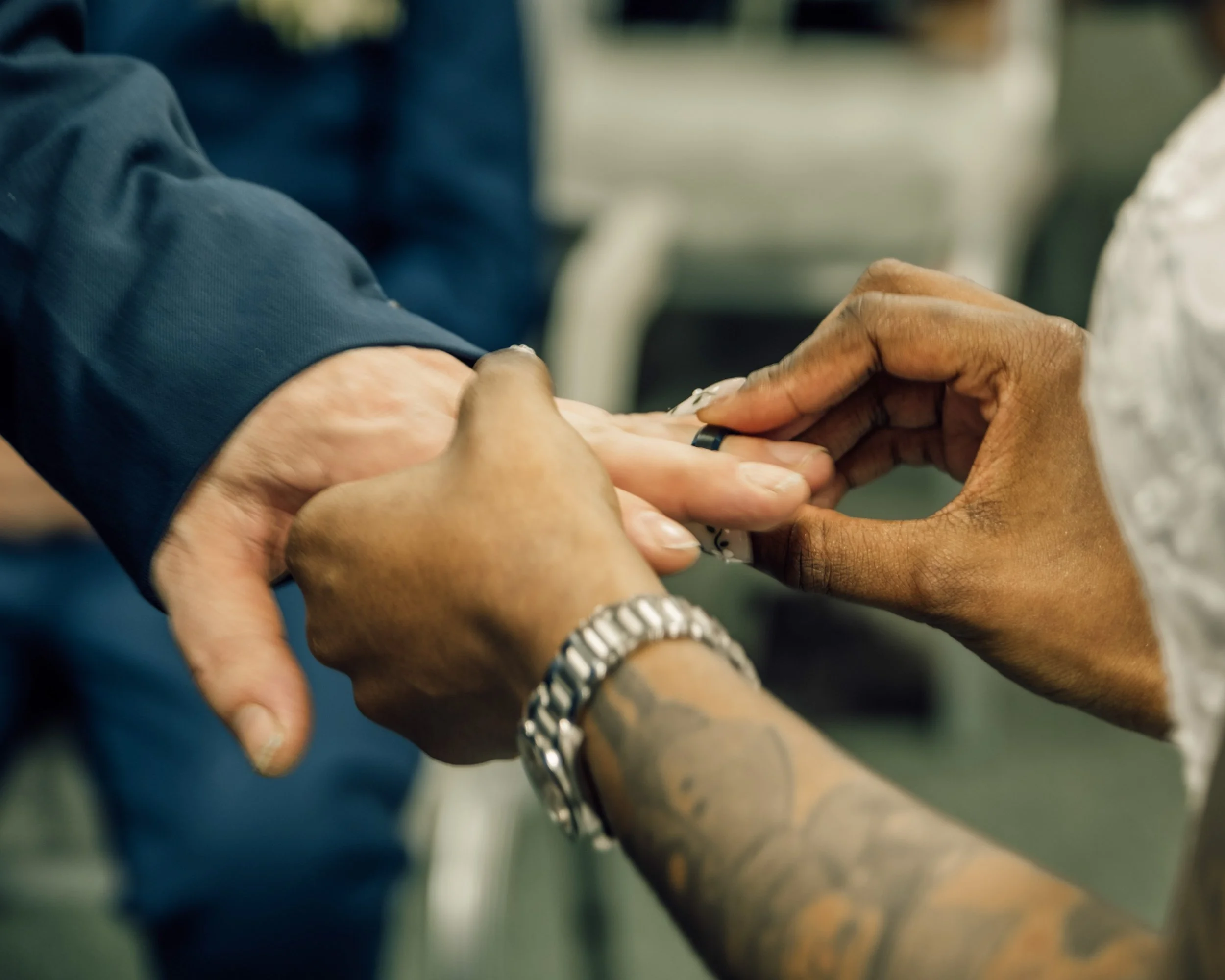 Close-up of two hands holding and exchanging a ring, suggesting a moment of engagement or marriage.