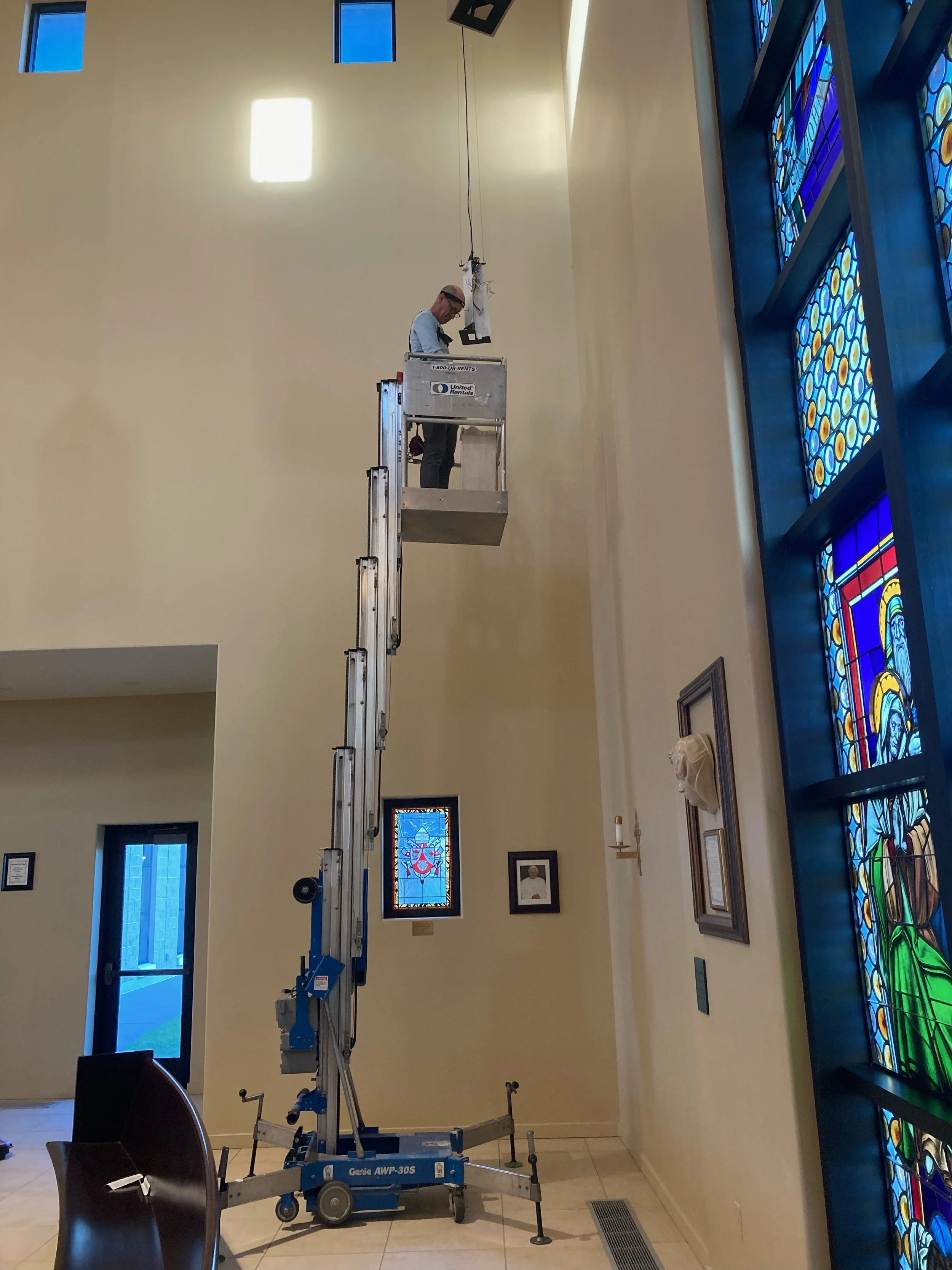 A person operating a lift inside a building with stained glass windows.