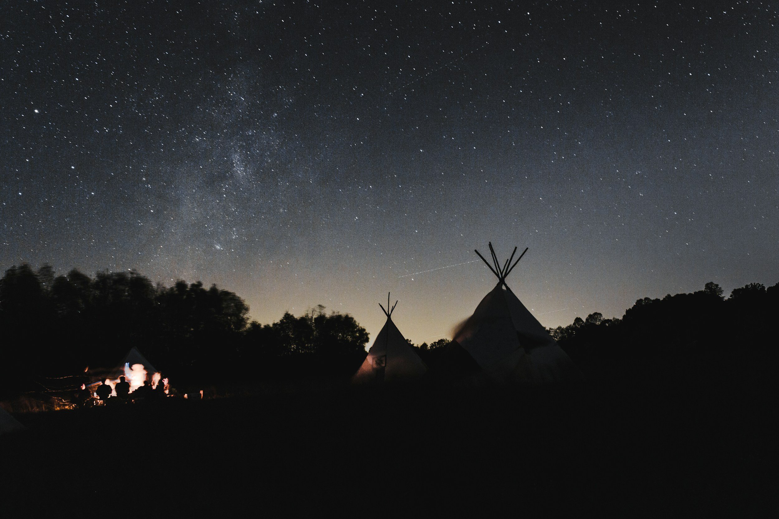 Teepees under a star-filled night sky representing Indigenous community and NIHB mental health support in Edmonton.
