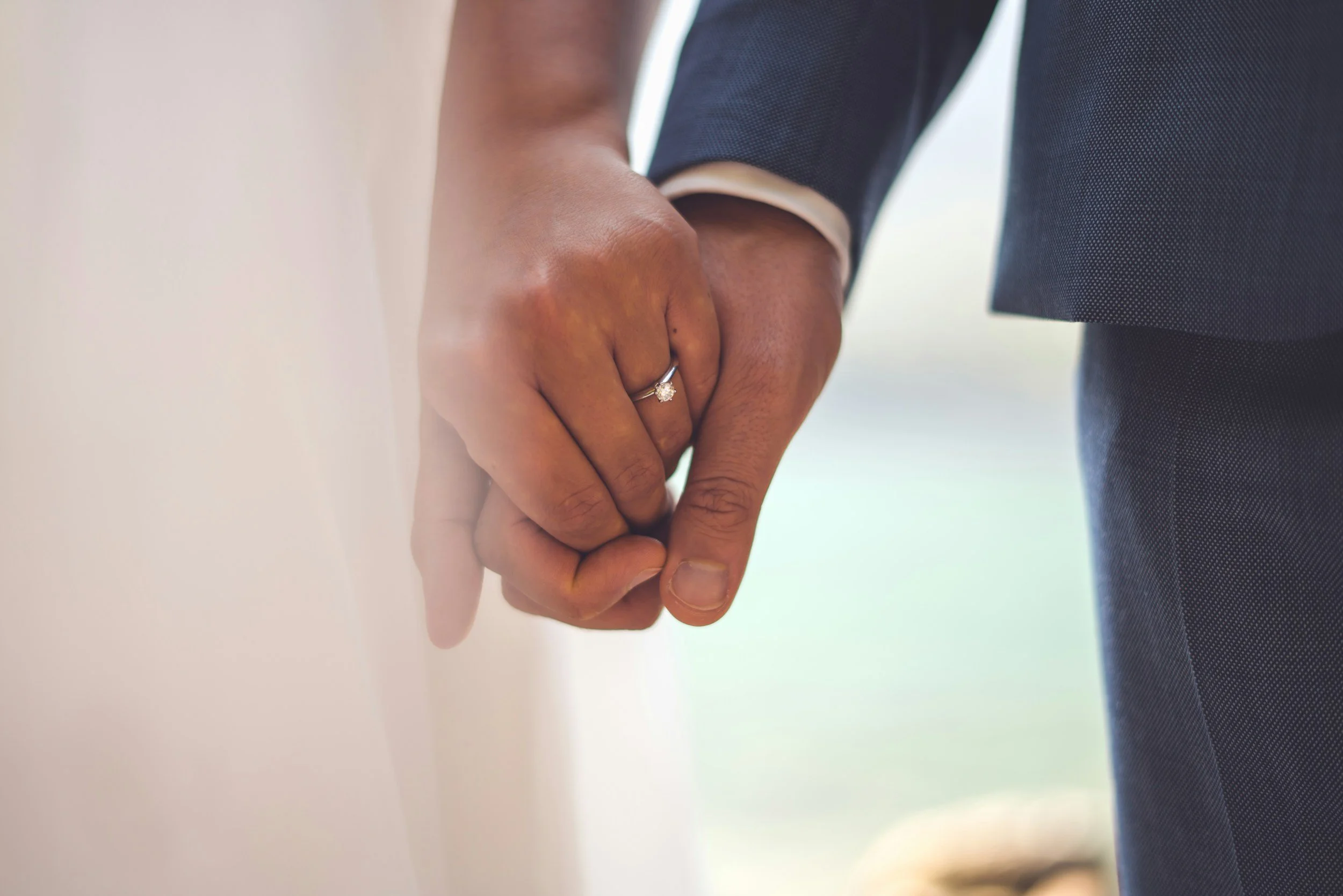 Close-up of engaged couple holding hands with wedding ring visible, representing marriage preparation and pre-marital counselling.