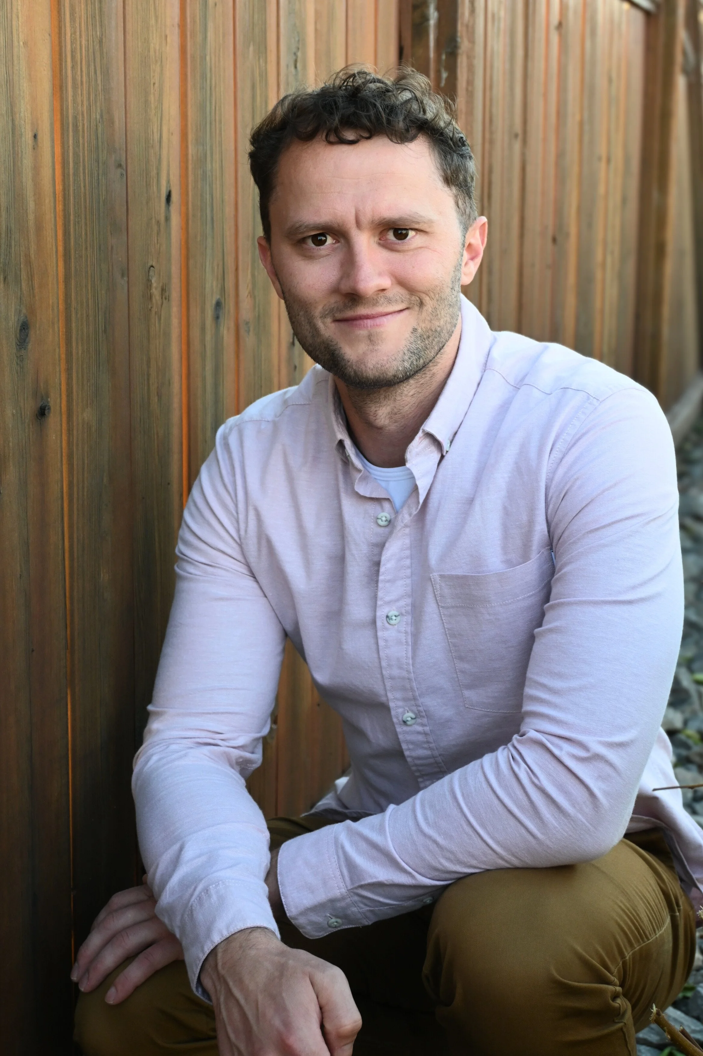 Carson Keeler, Registered Social Worker offering men's counselling in Edmonton, smiling in a light button-up shirt