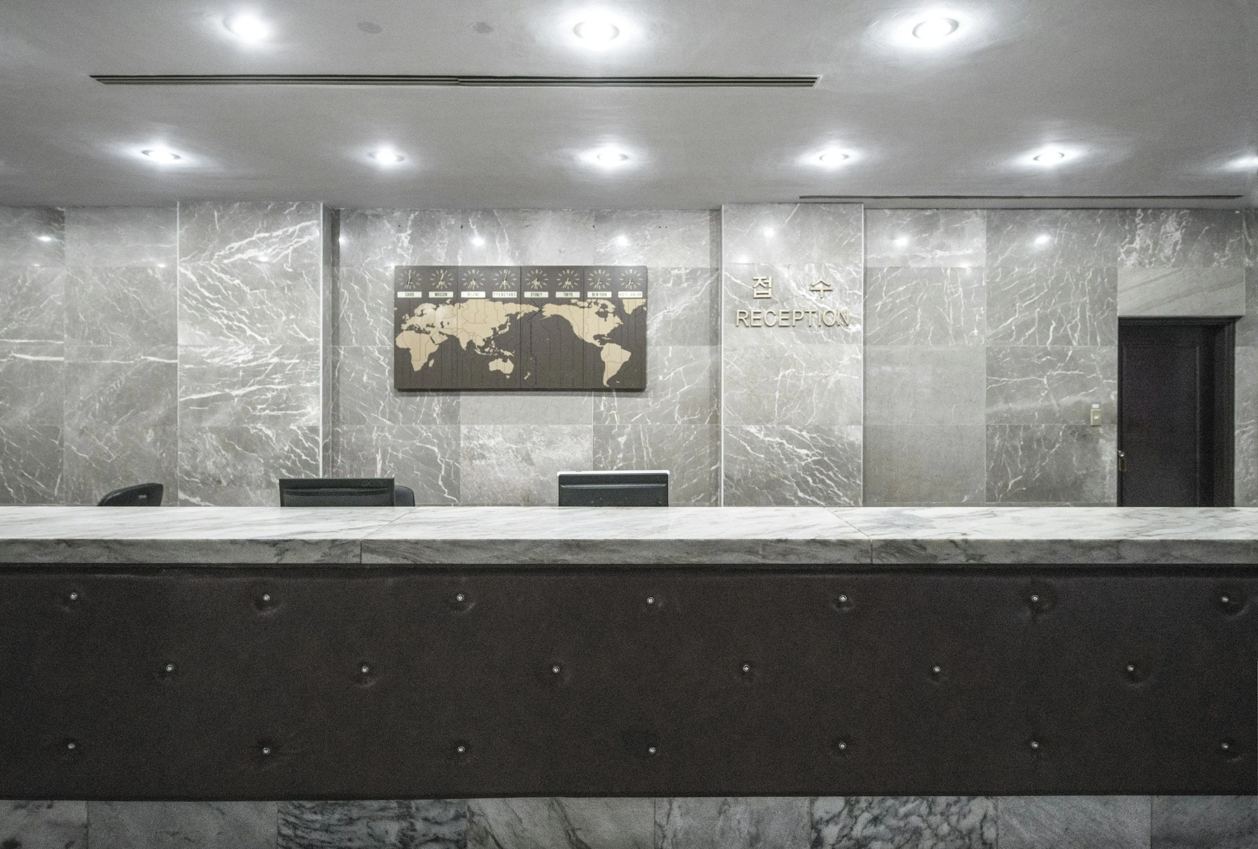 Hotel reception desk with grey marble walls and a stone countertop, an example of commercial countertop protection protected by Stone Shield Calgary.