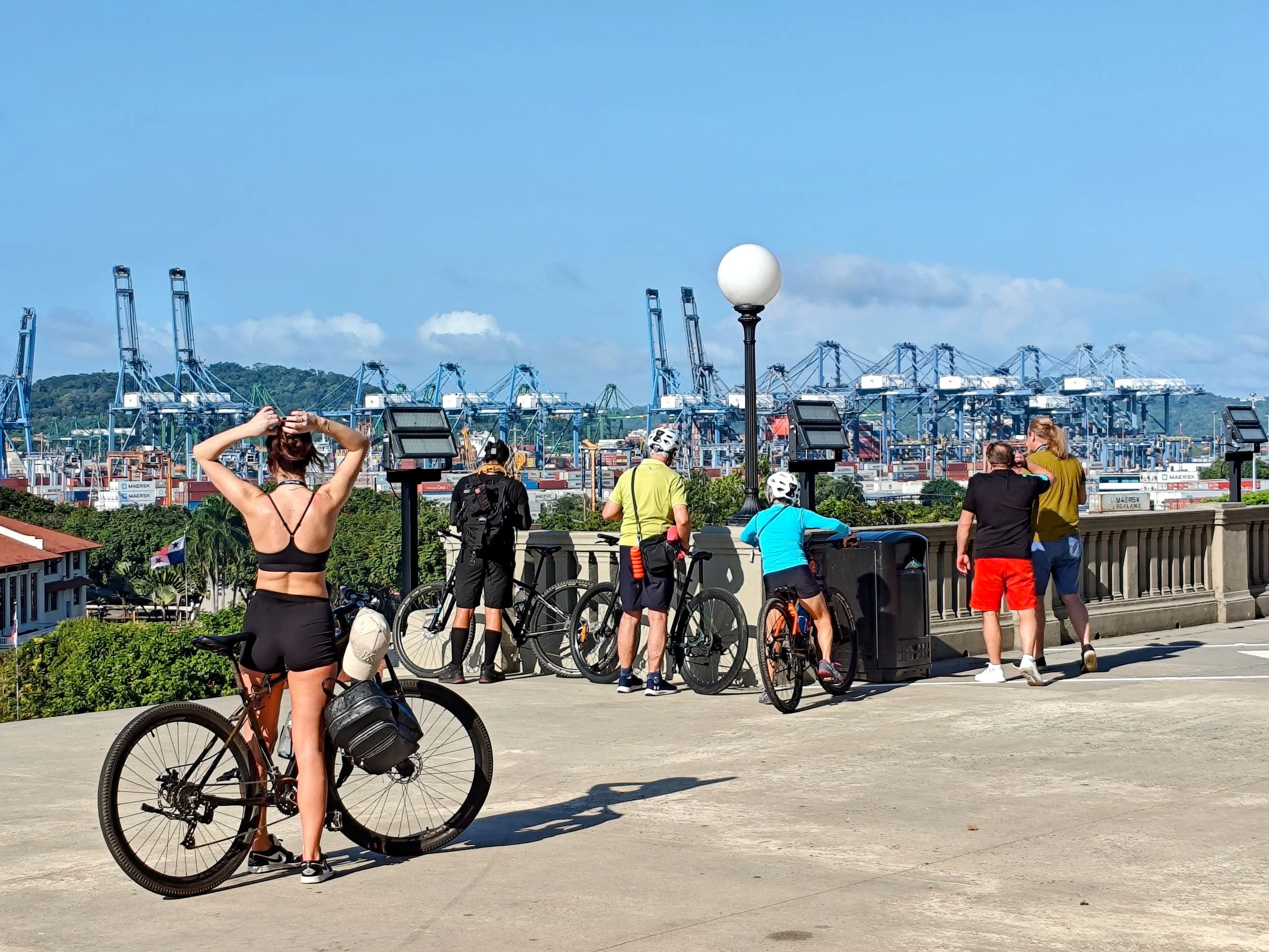 Cyclists overlooking container cranes at the Port of Balboa during the Panama Canal Zone Bike Tour.