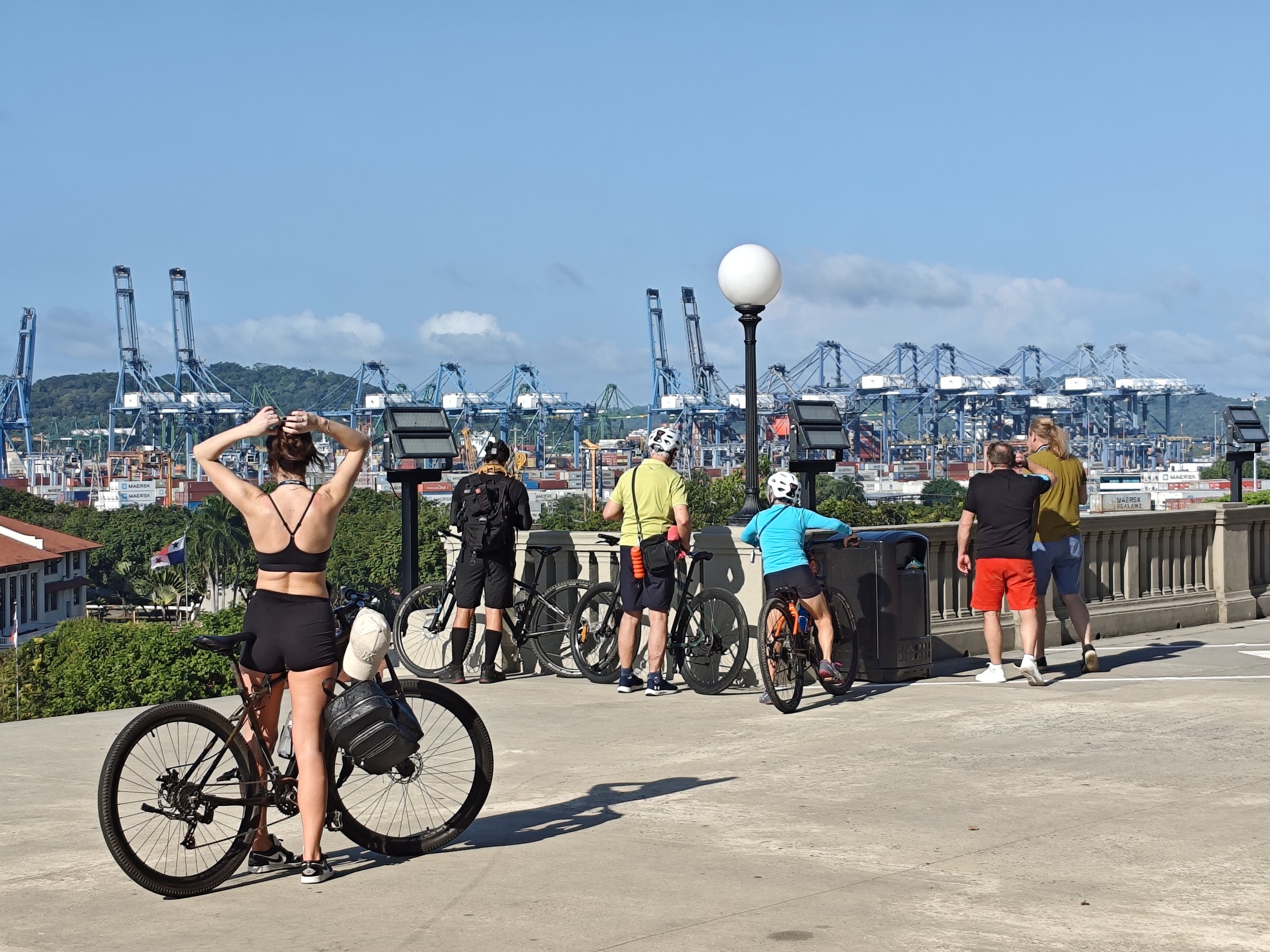 Cyclists overlooking container cranes at the Port of Balboa during the Panama Canal Zone Bike Tour.