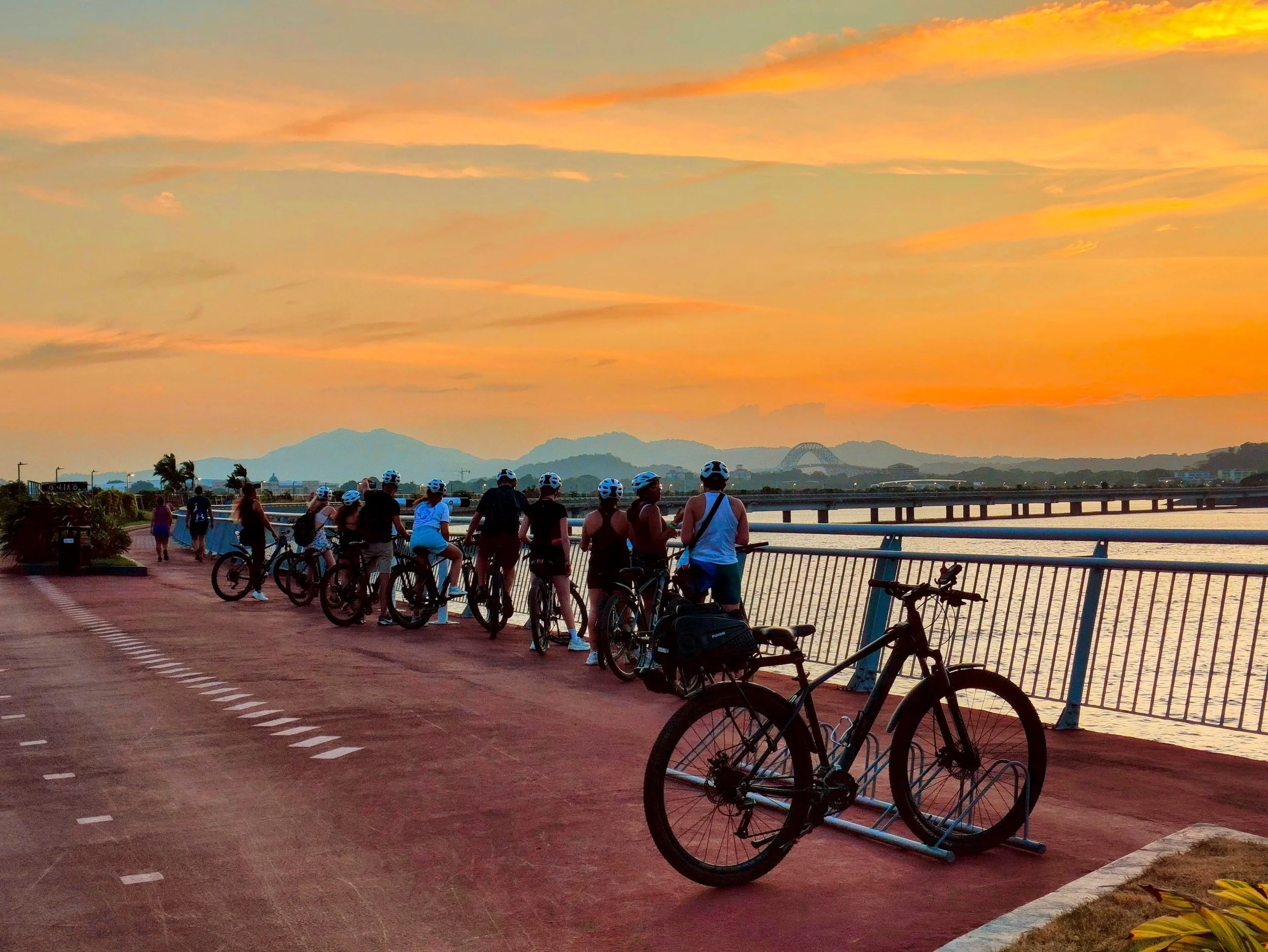 Cyclists riding along Cinta Costera at sunset during the Panama City Sunset Bike Tour.