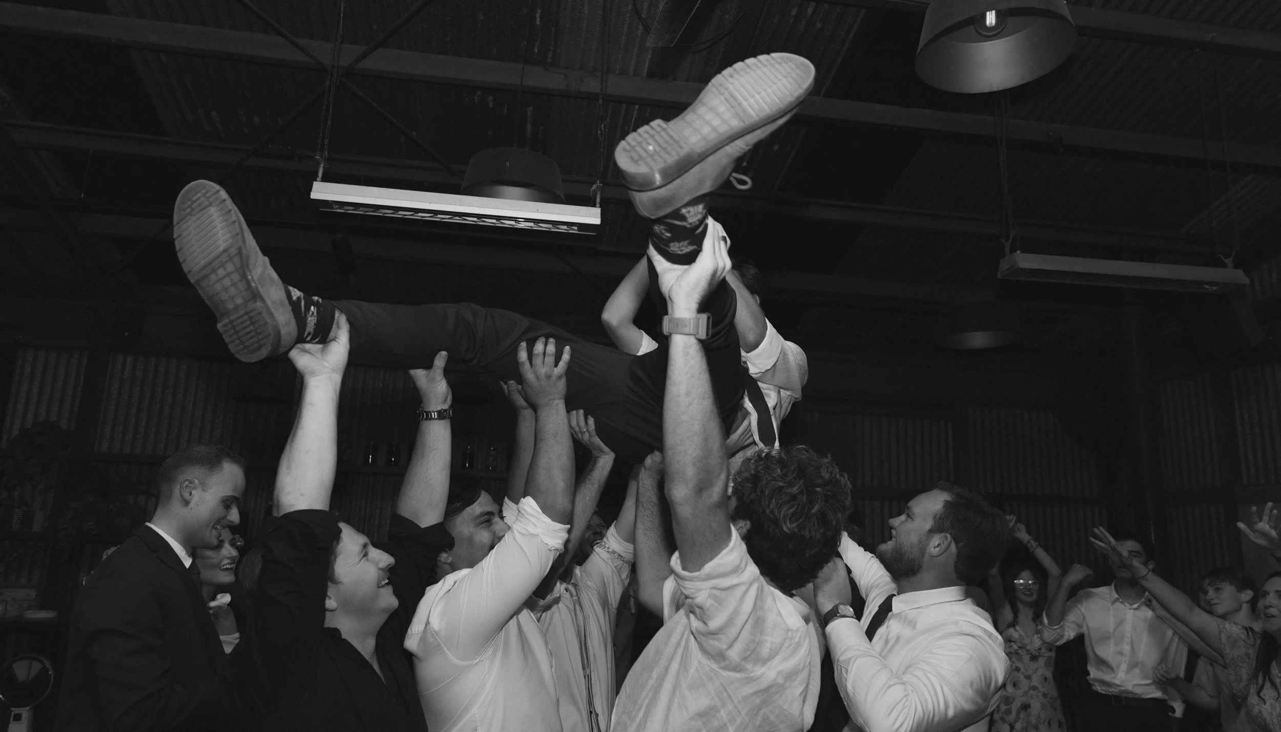 Group of people celebrating and lifting a person in a party or event setting.