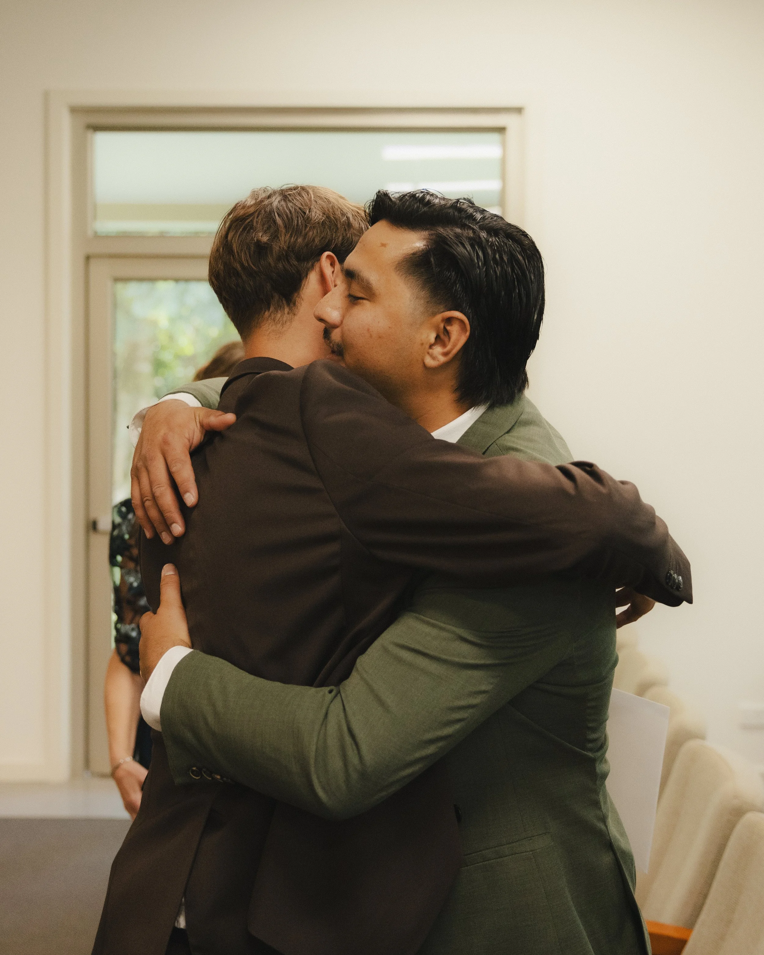 Two men hugging each other warmly in a room.