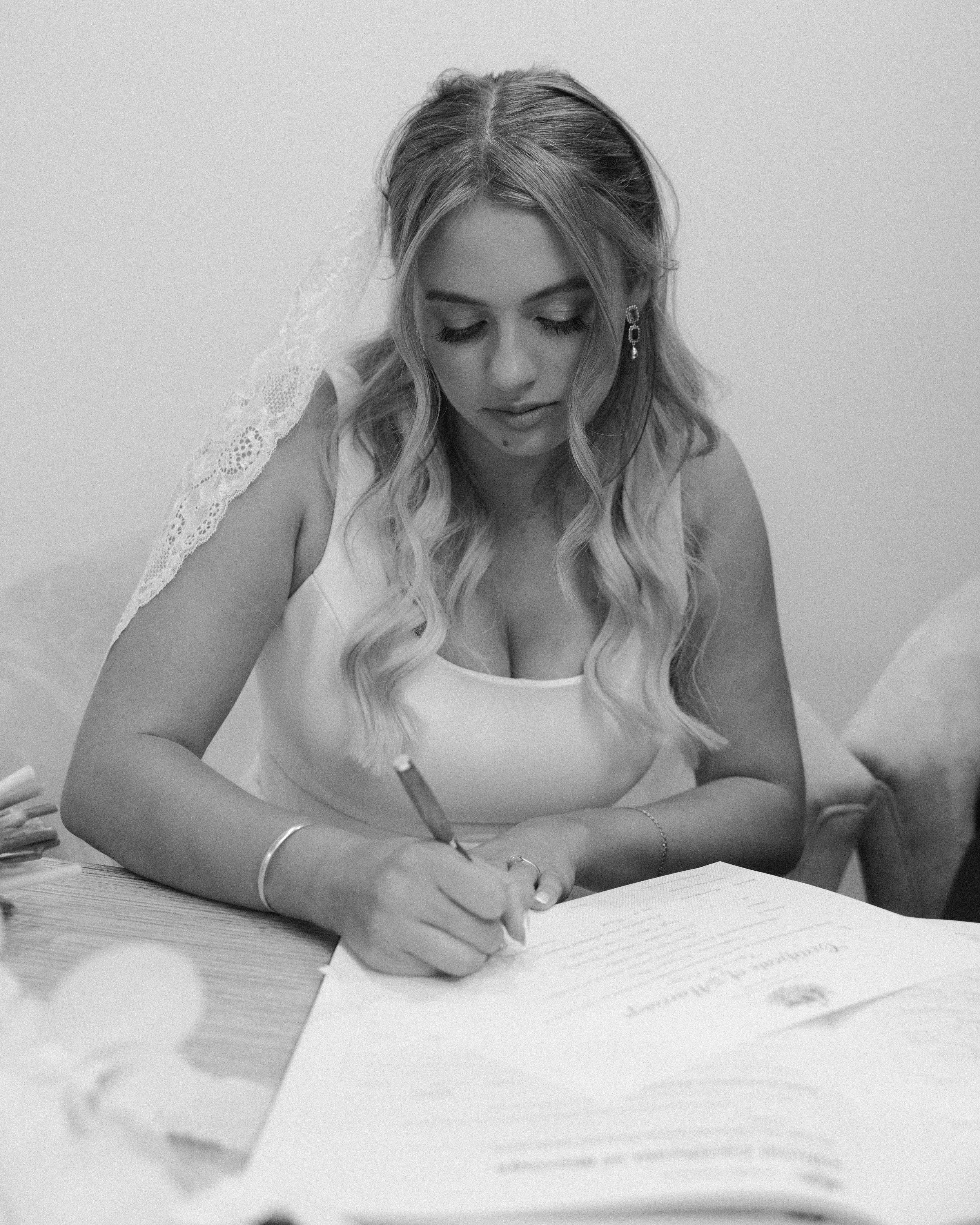A woman in a wedding dress signing a document.