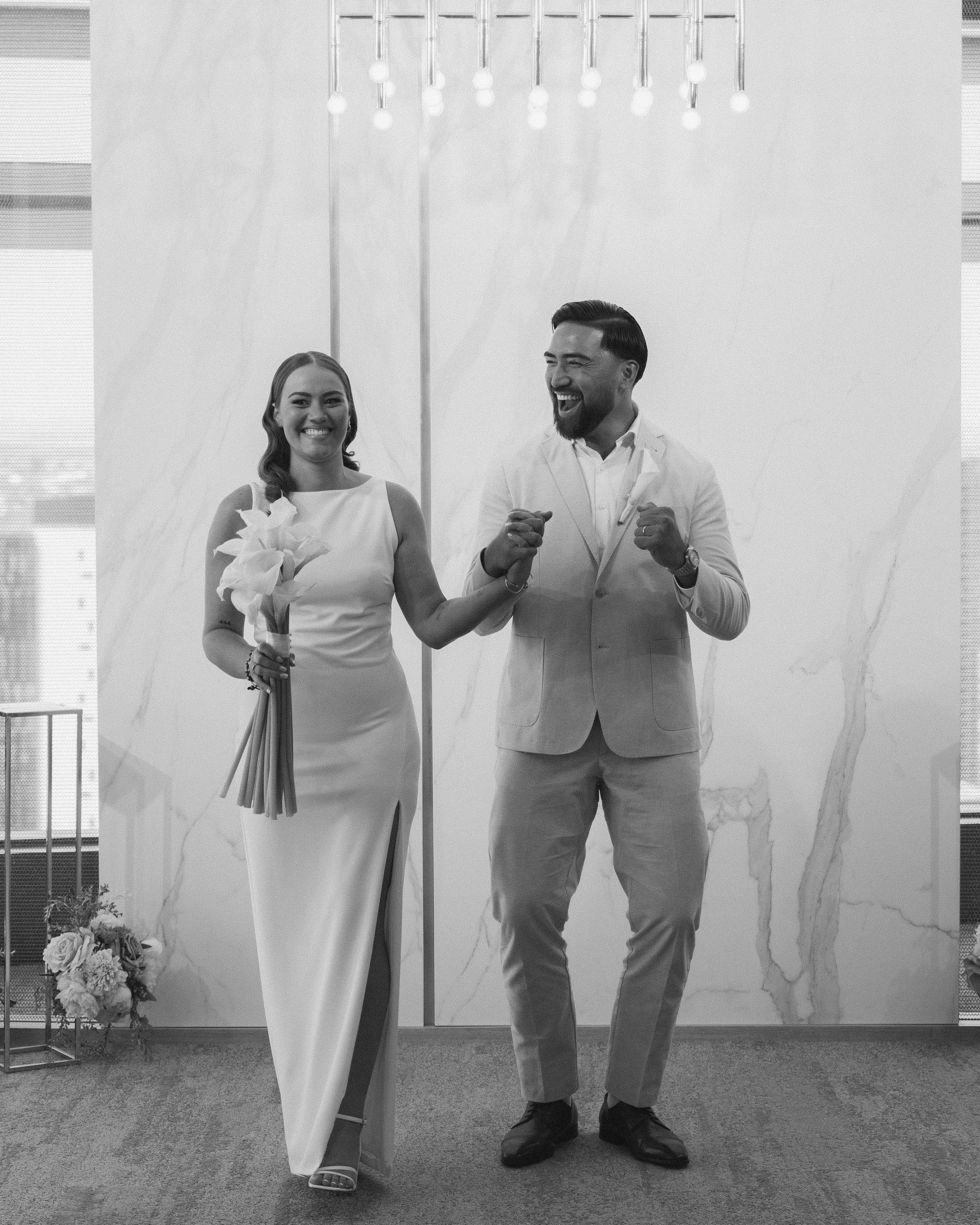 A happy couple in formal attire celebrating their wedding in an indoor setting.