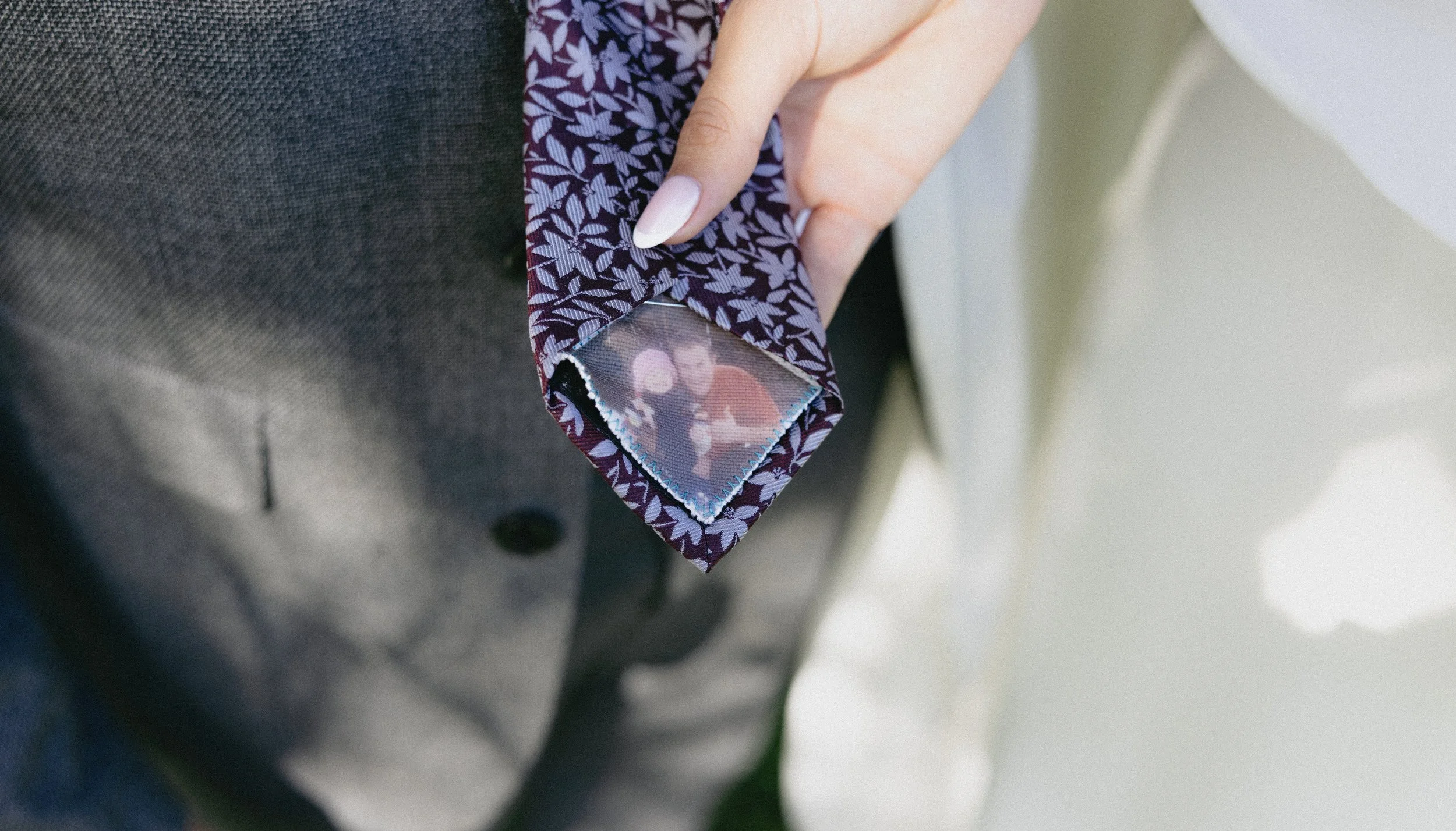 Close-up of a person's blazer with a photograph of two people pinned to the sleeve.