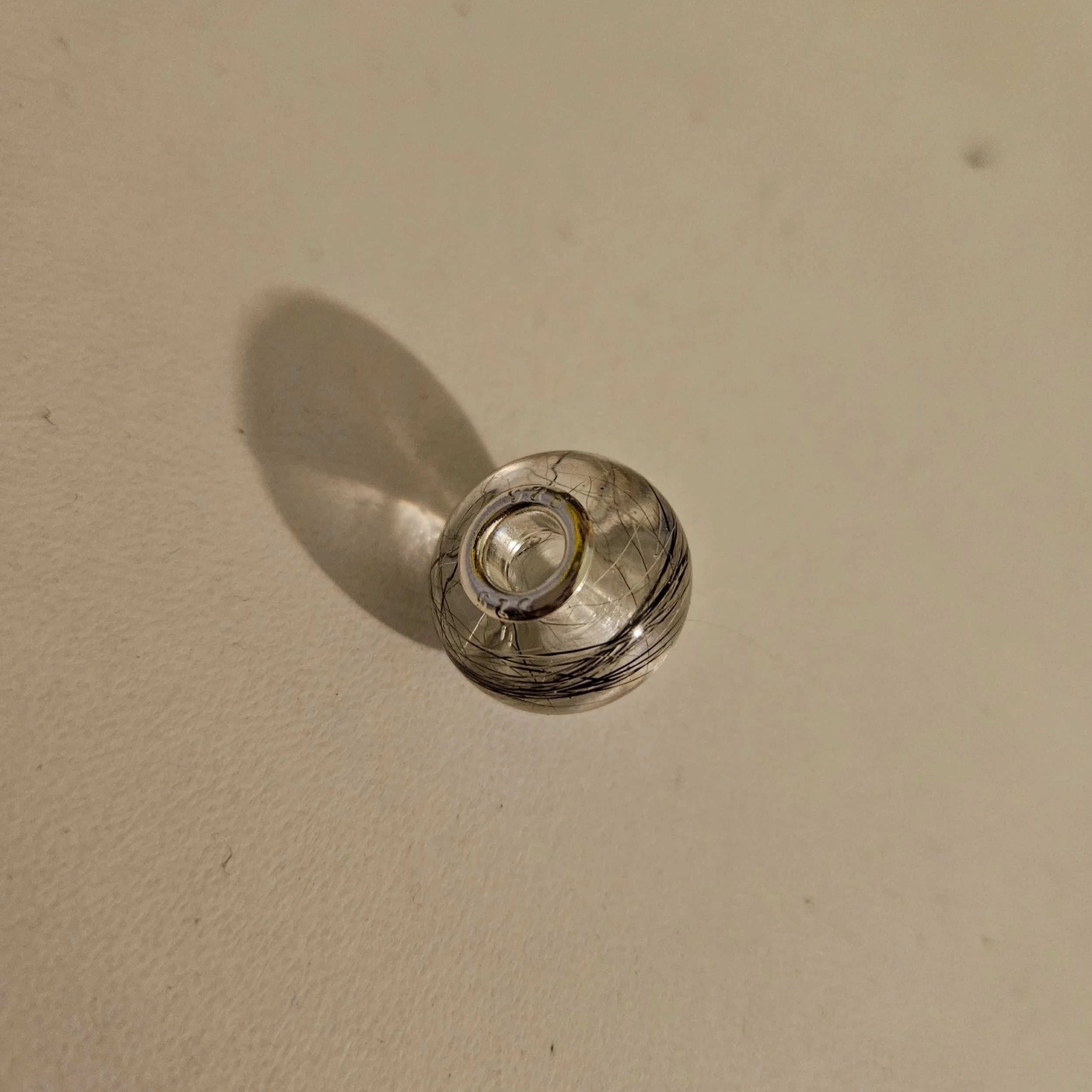 Close-up of a resin Pandora-style bead encasing a beloved pets hair finished with sterling silver core