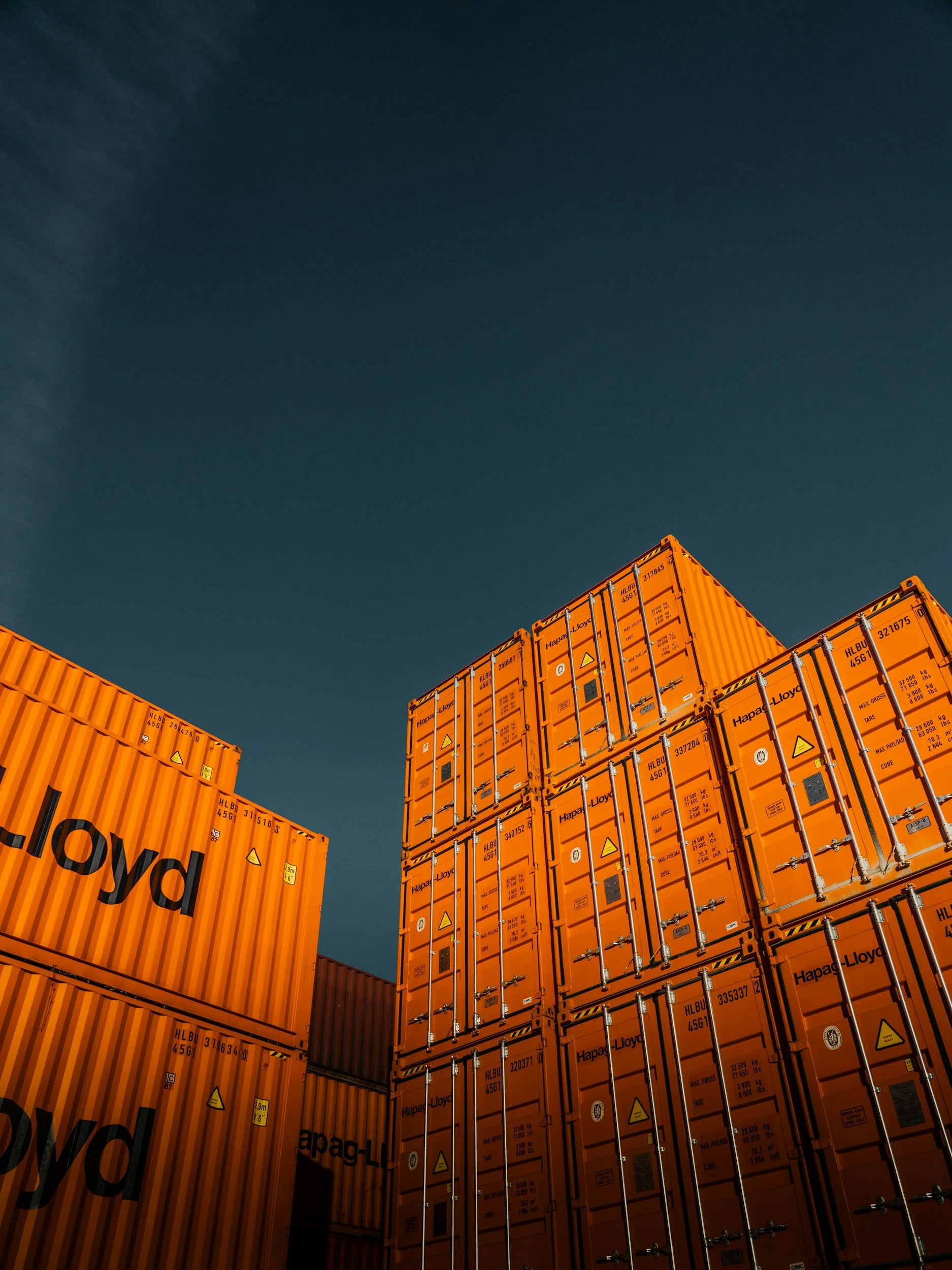 Stacked orange shipping containers against a dark sky.