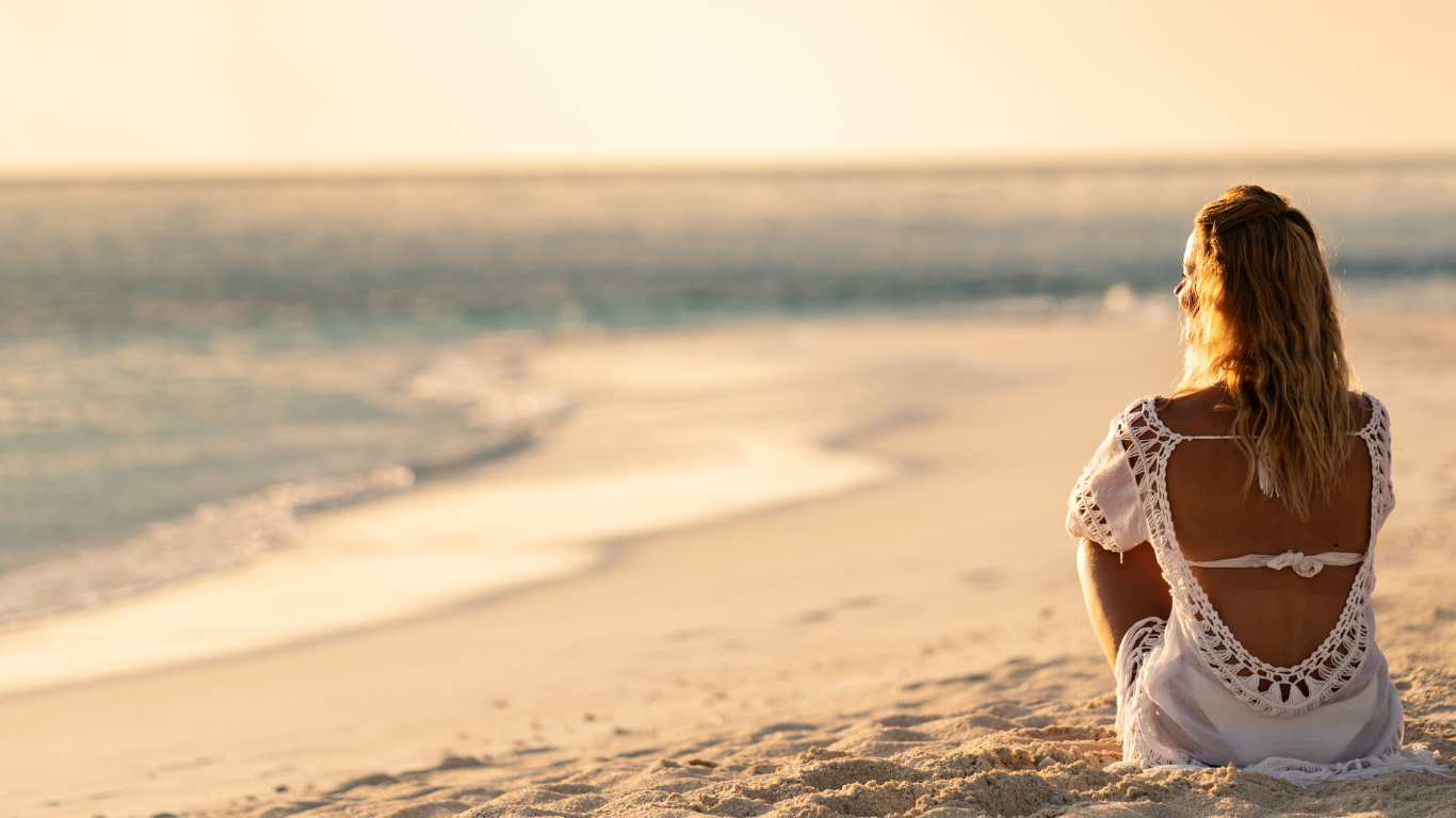 Fabienne Delbouis assise sur la plage de Sainte Barbe, face à l'horizon