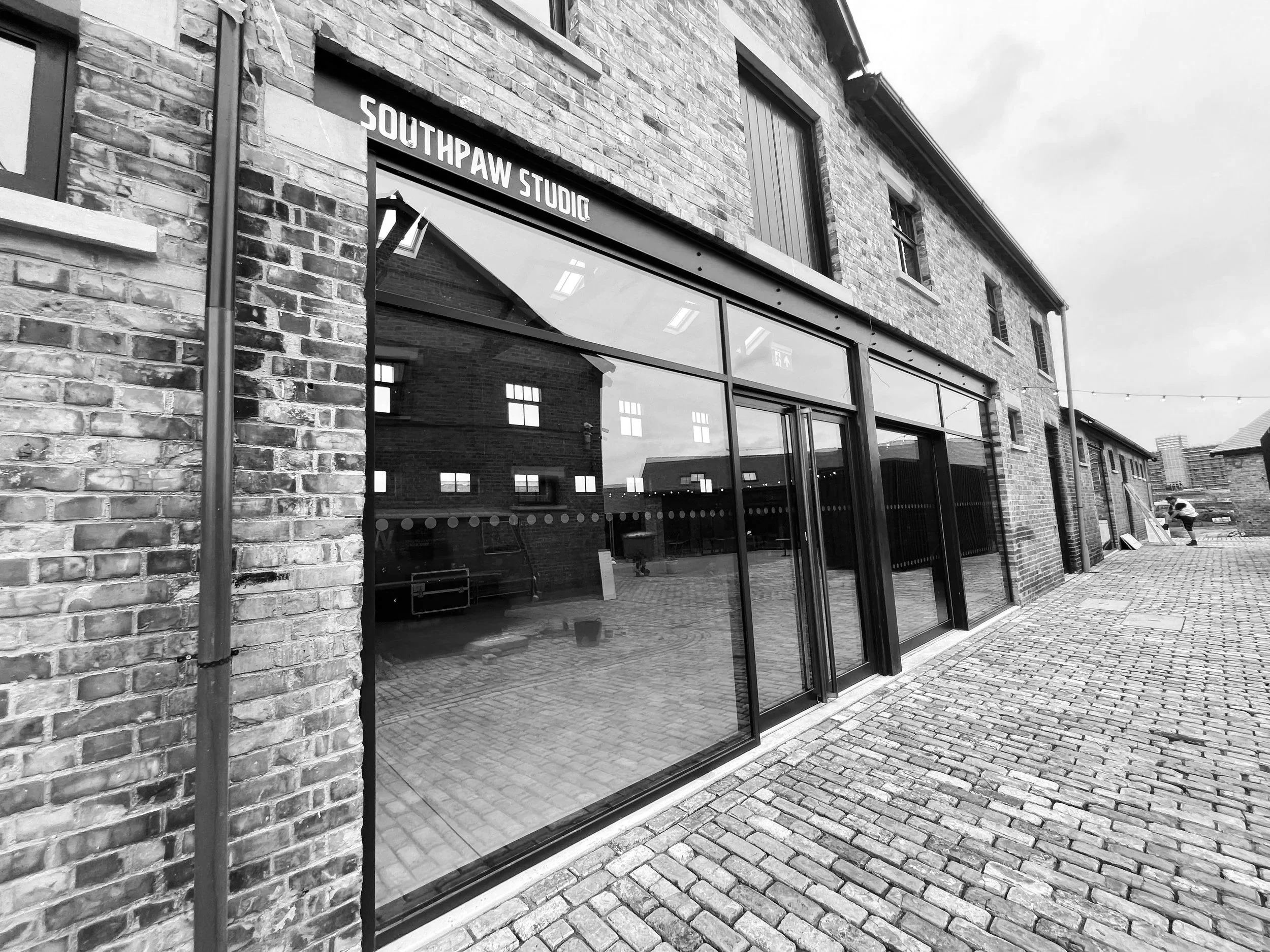 red brick stable building with glass front. sign says southpaw studio
