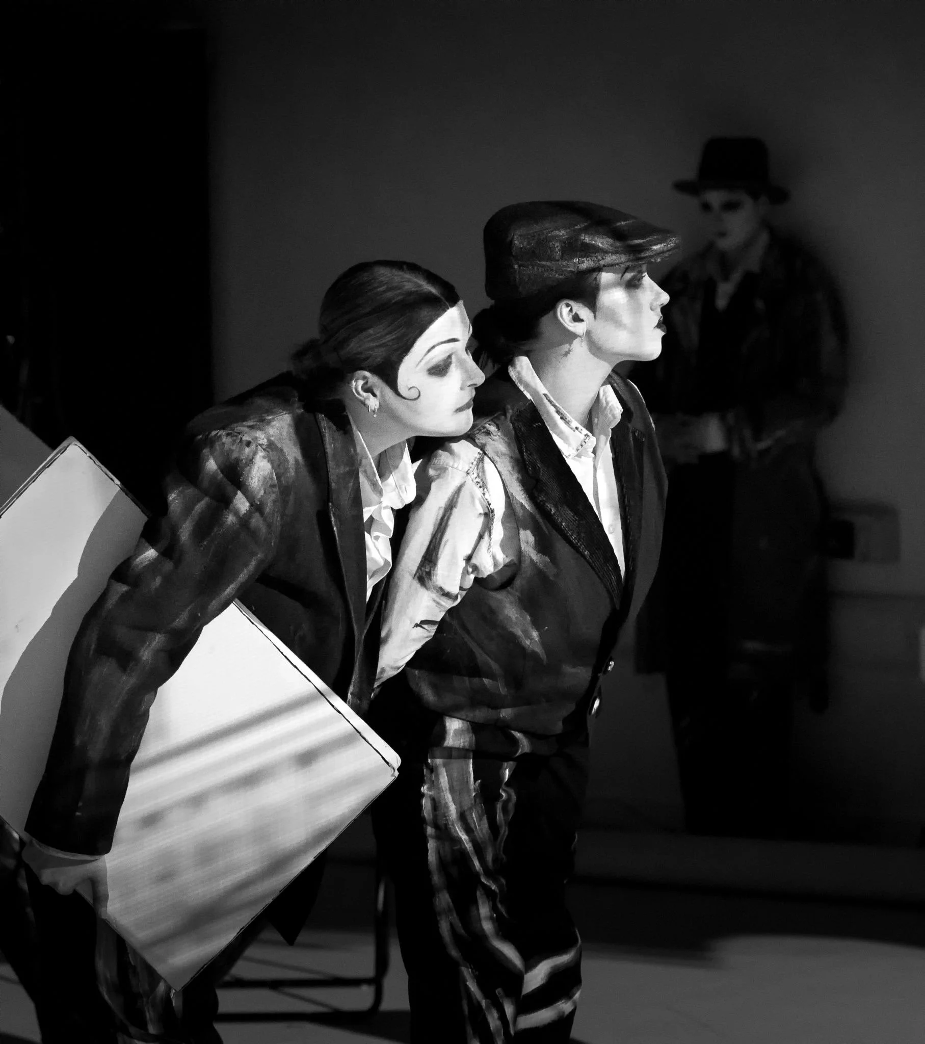 black and white image of 2 women in waistcoats and flat caps look to the right