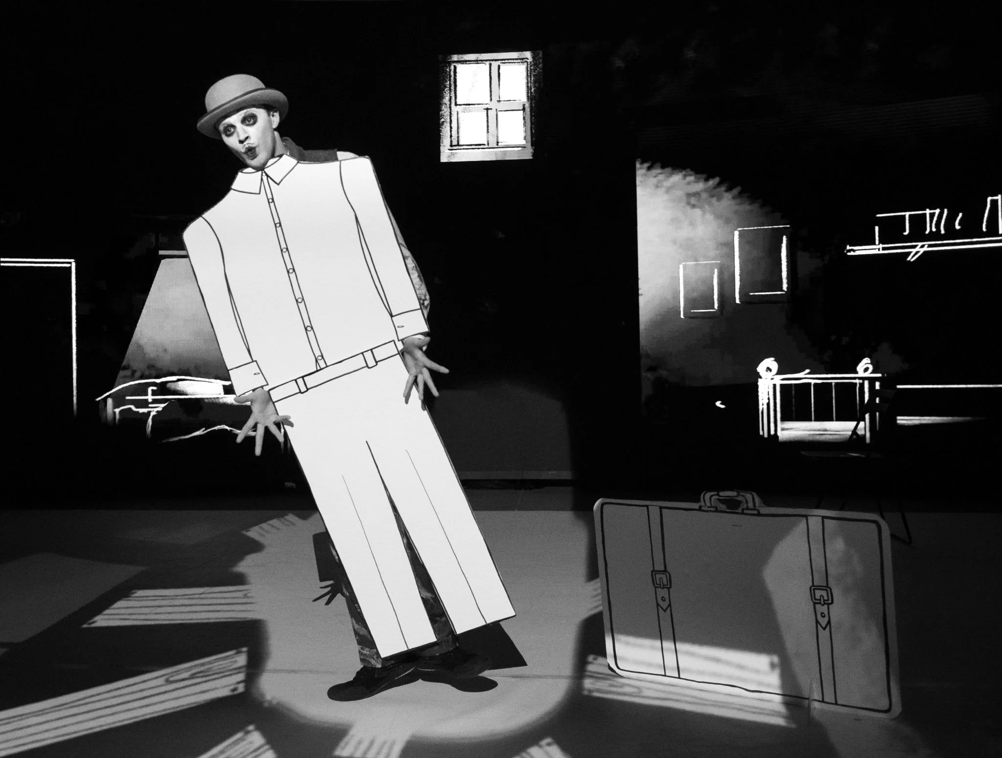 black and white image of man stood behind a cardboard prop of a suit looking shocked