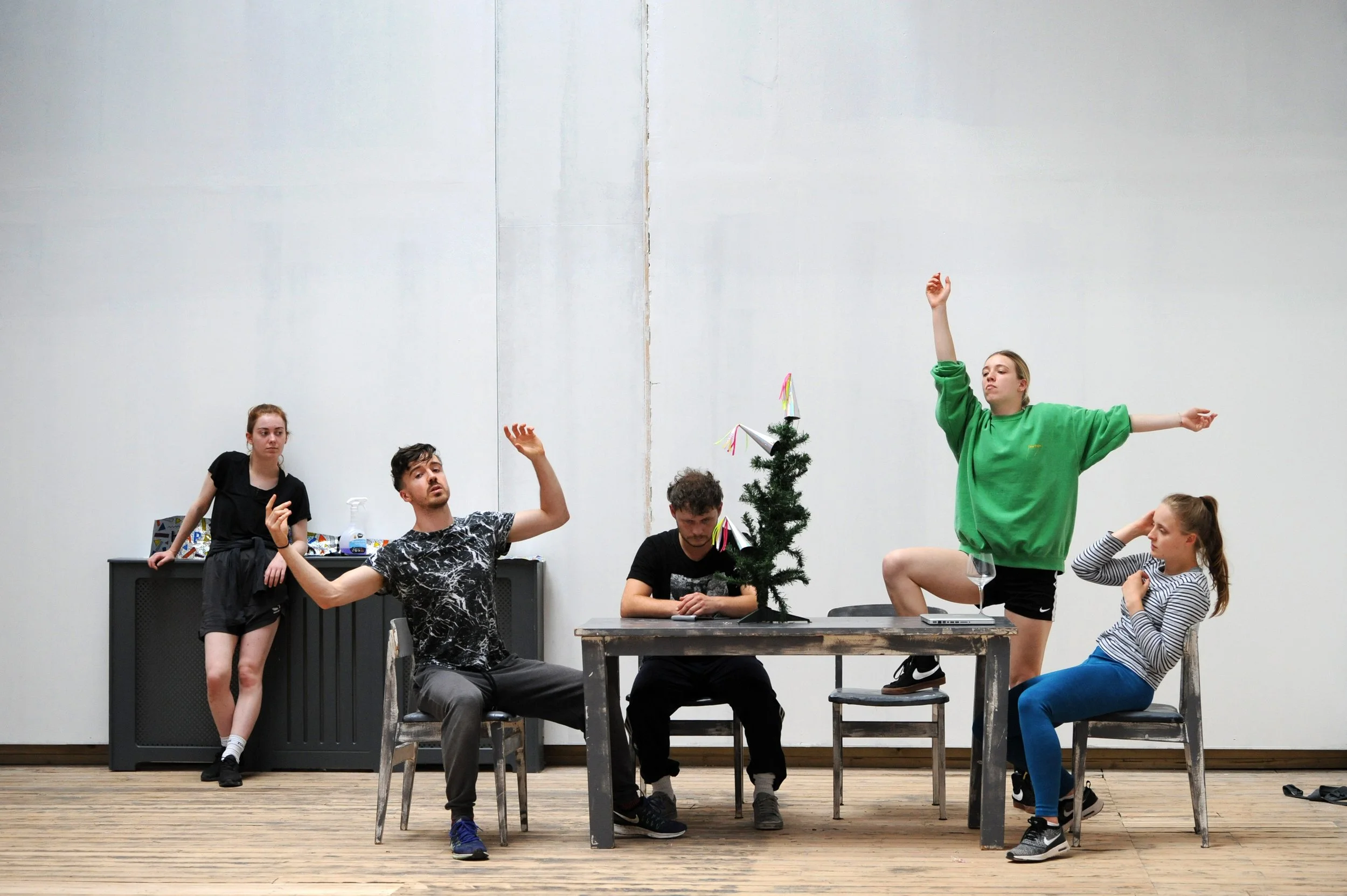 group of 5 dancers pose around a dining table and chairs