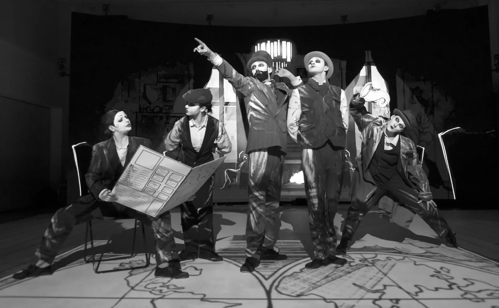 black and white image of 5 dancers all posing around a large newspaper