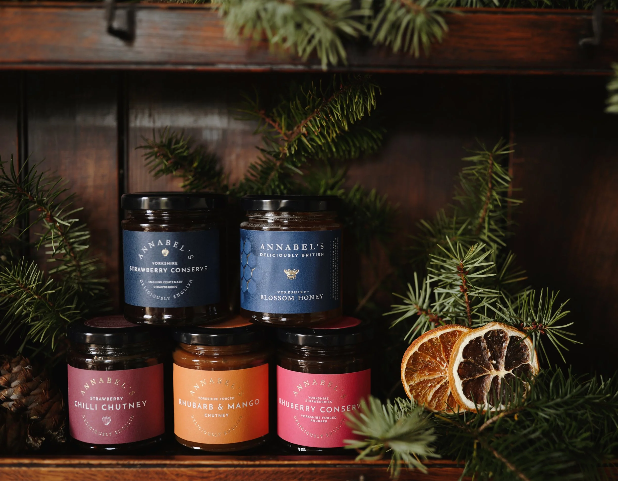 Festive collection of Annabel's Deliciously British products with dried orange slices and pine tree branches