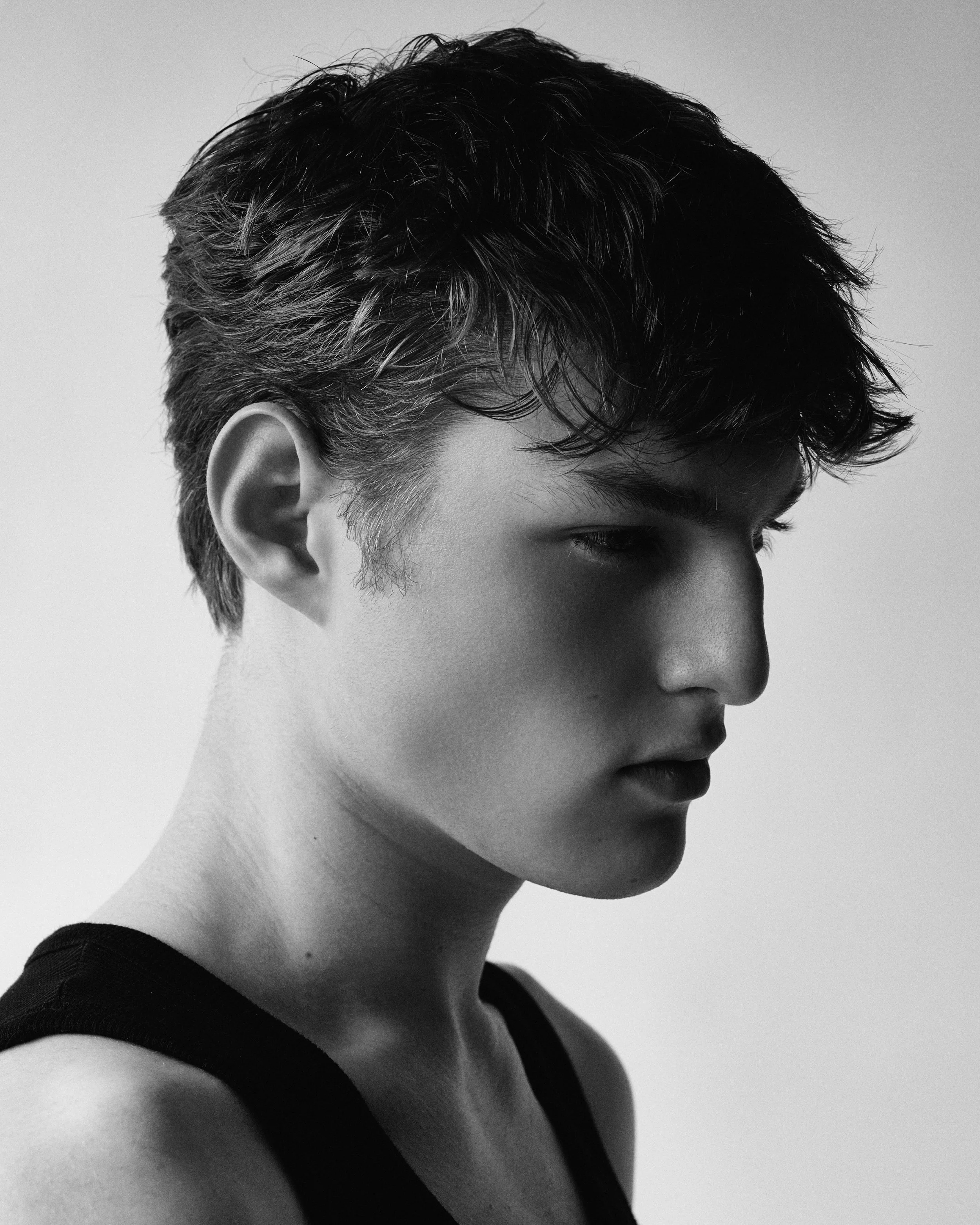 Black and white portrait of a young woman with short, tousled hair, wearing a sleeveless top, looking to her right.