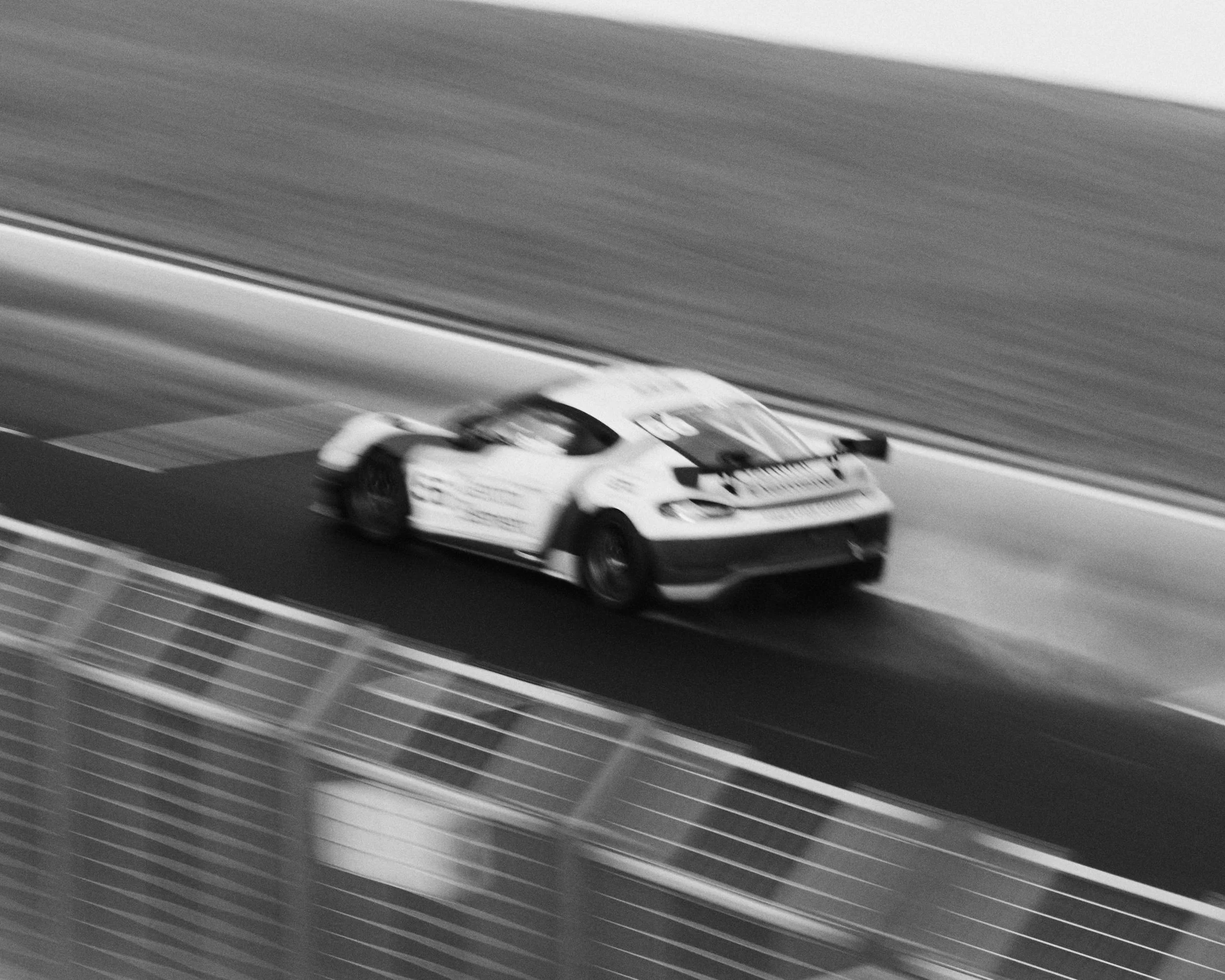 A race car moving at high speed on a race track, with a blurred background indicating motion.