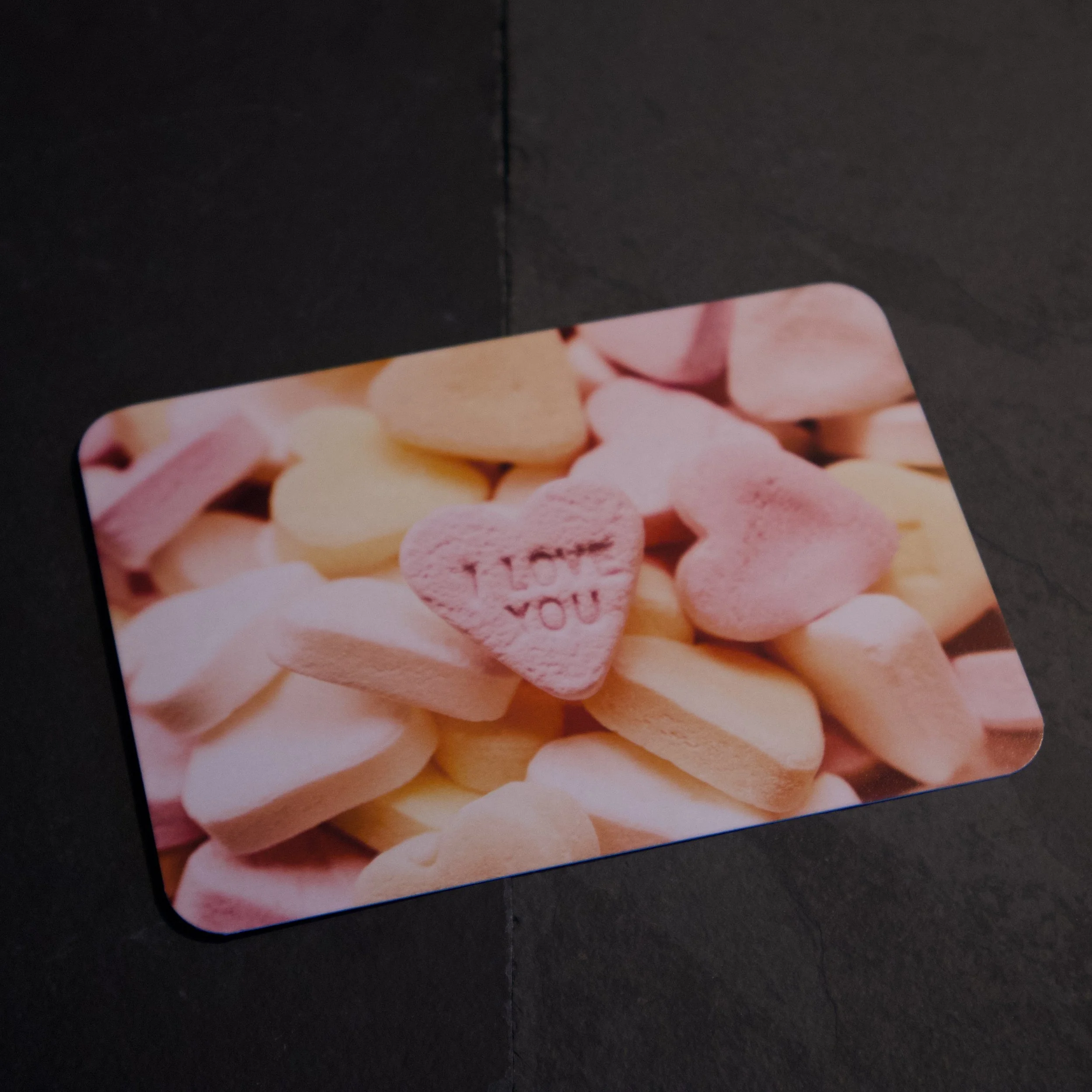 Candy Heart Interesting photograph of a pile of pink, orange, and yellow candy hearts with I LOVE YOU embossed into one - Salty Note