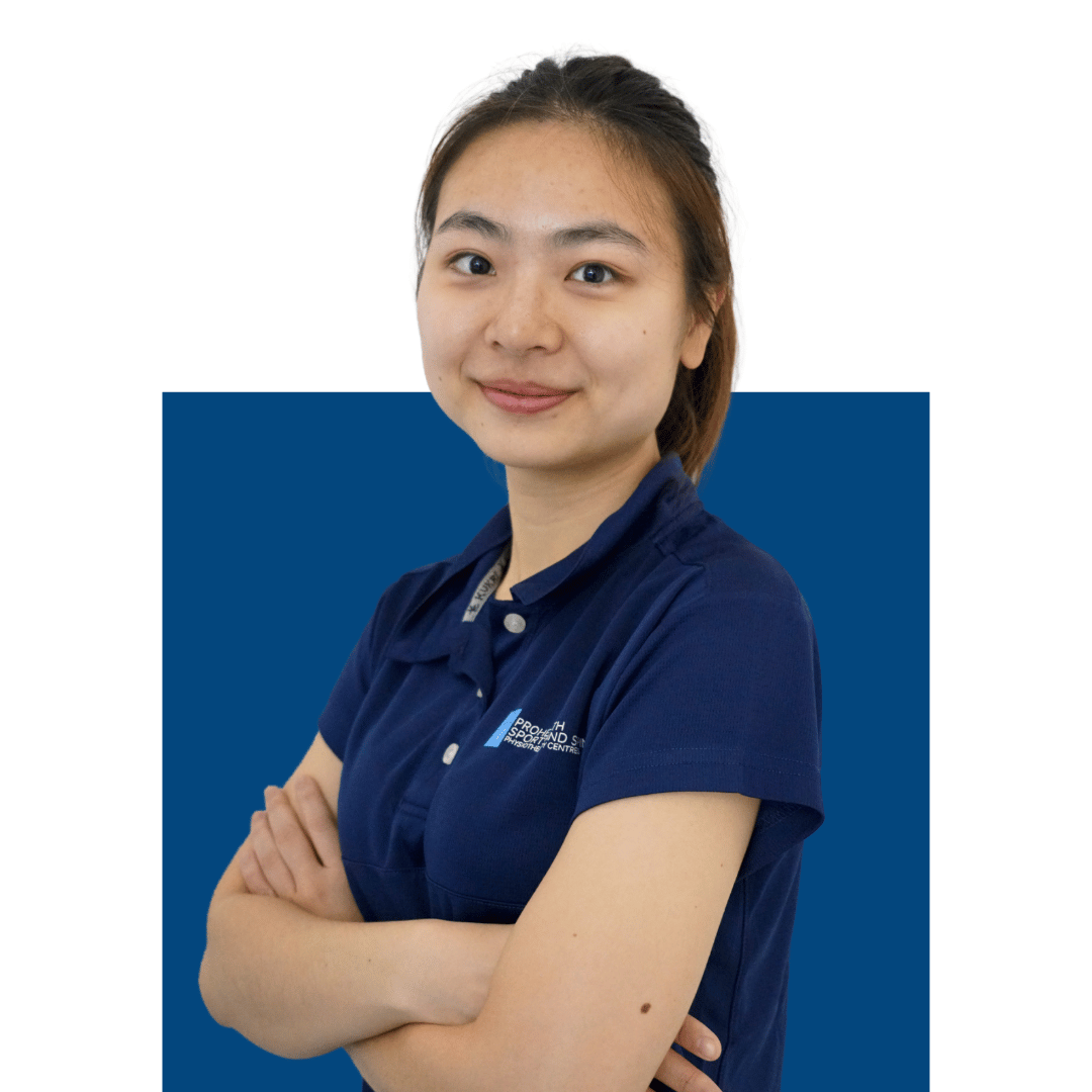 Young woman with dark hair in a ponytail, smiling, wearing a navy polo shirt with logo, standing with crossed arms against a white and blue background.