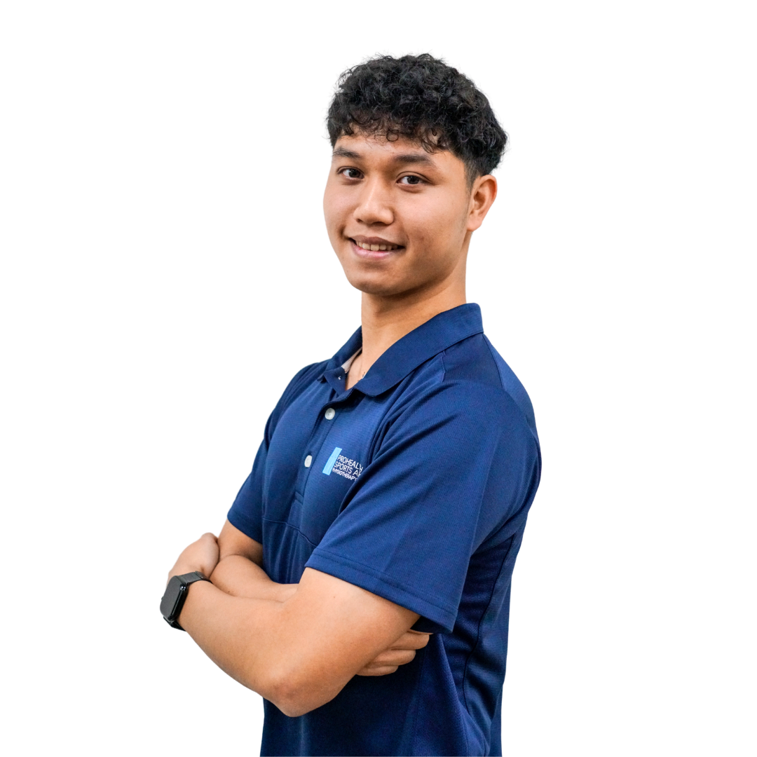 Young man with curly black hair wearing a navy blue polo shirt, standing with arms crossed, smiling, against a white background.